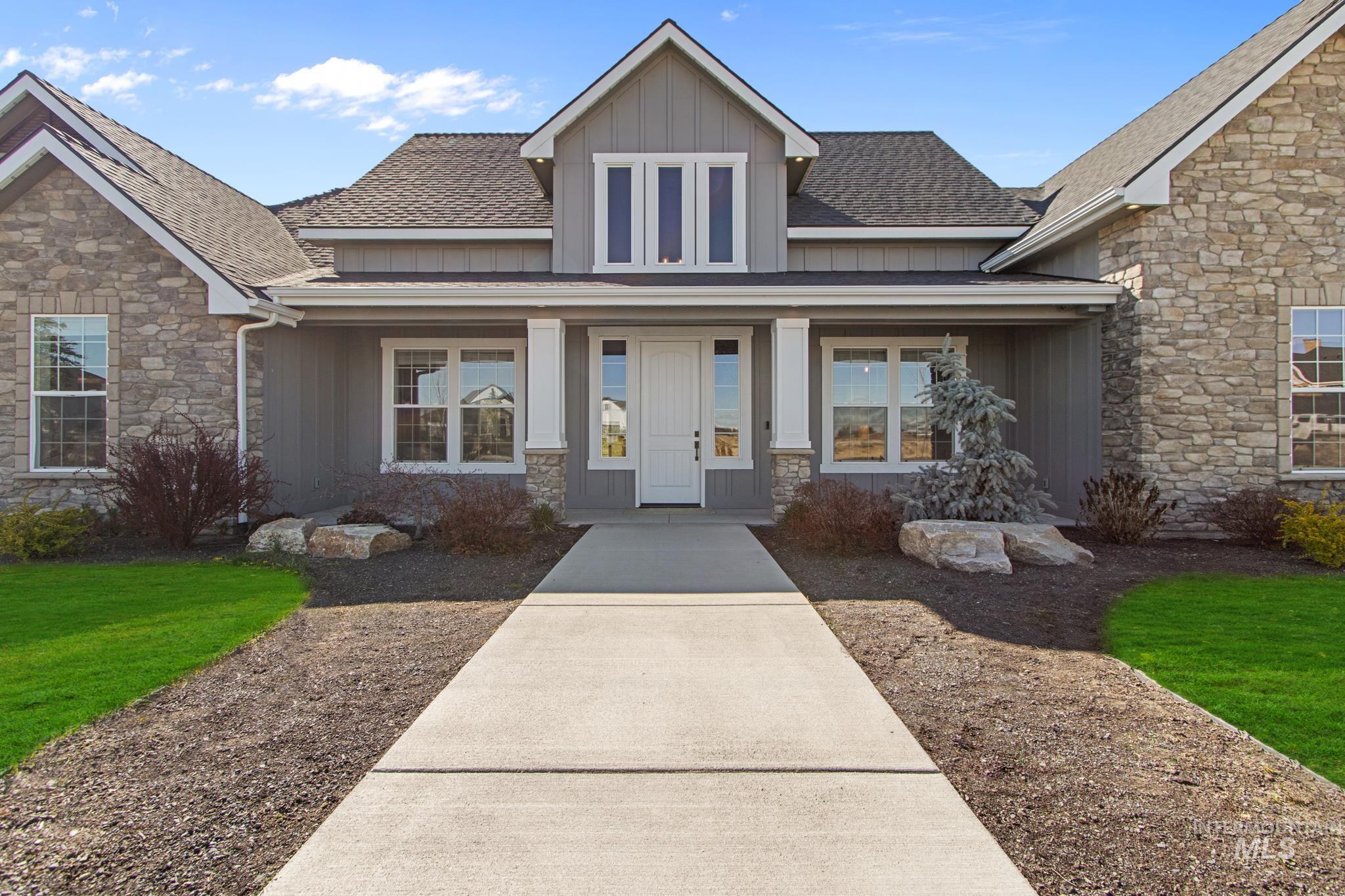 Craftsman-style house with roof with shingles, stone siding, board and batten siding, covered porch, and a front yard