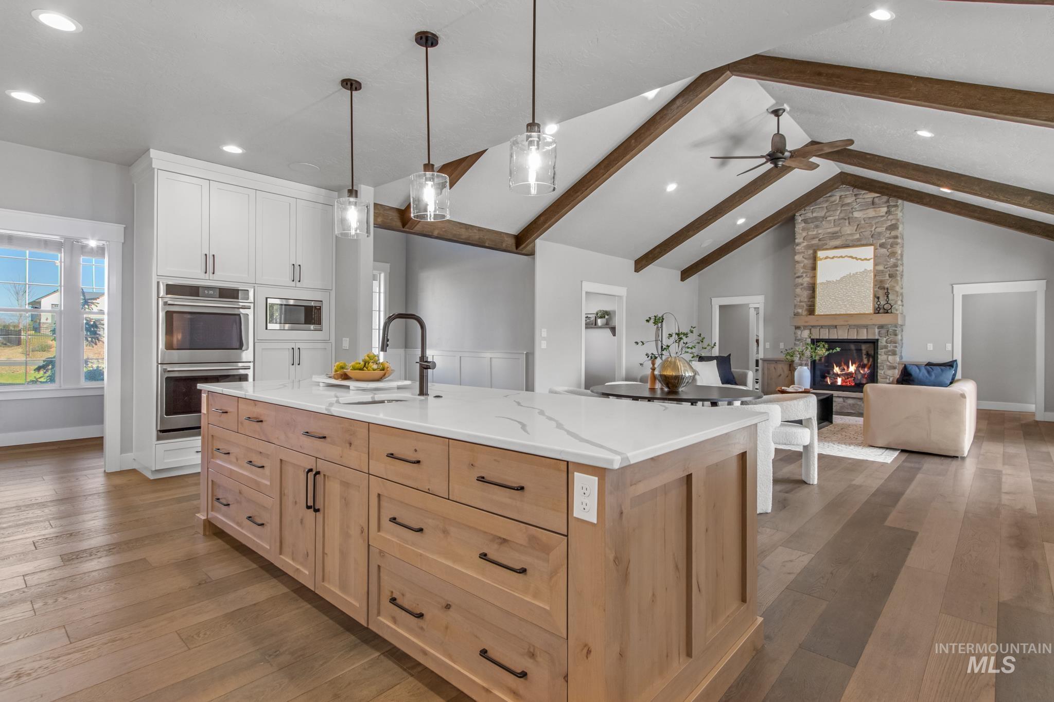 Kitchen with light wood-type flooring, two tone color scheme, an island with sink, open floor plan, and stainless steel appliances