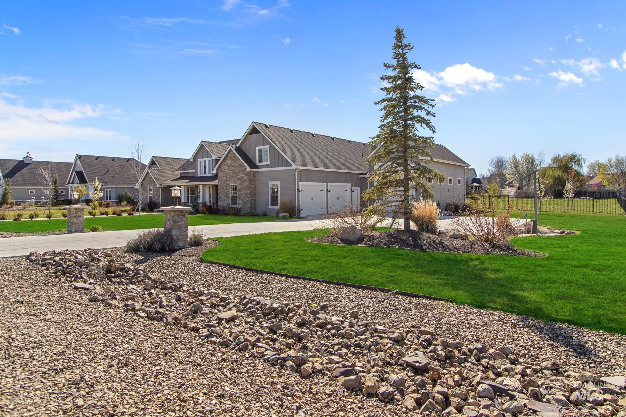 View of front of house with stone siding, concrete driveway, a residential view, and a garage