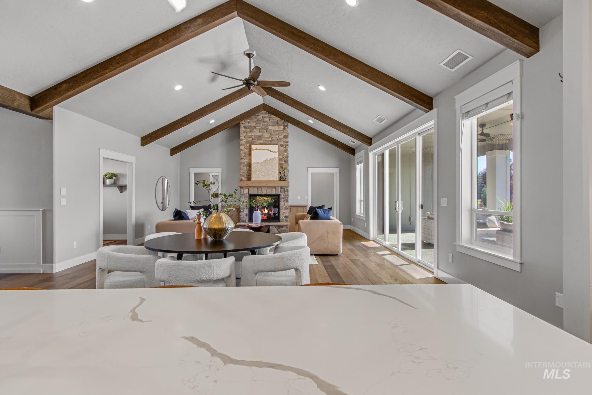 Dining room with light wood-style floors, a stone fireplace, ceiling fan, and recessed lighting