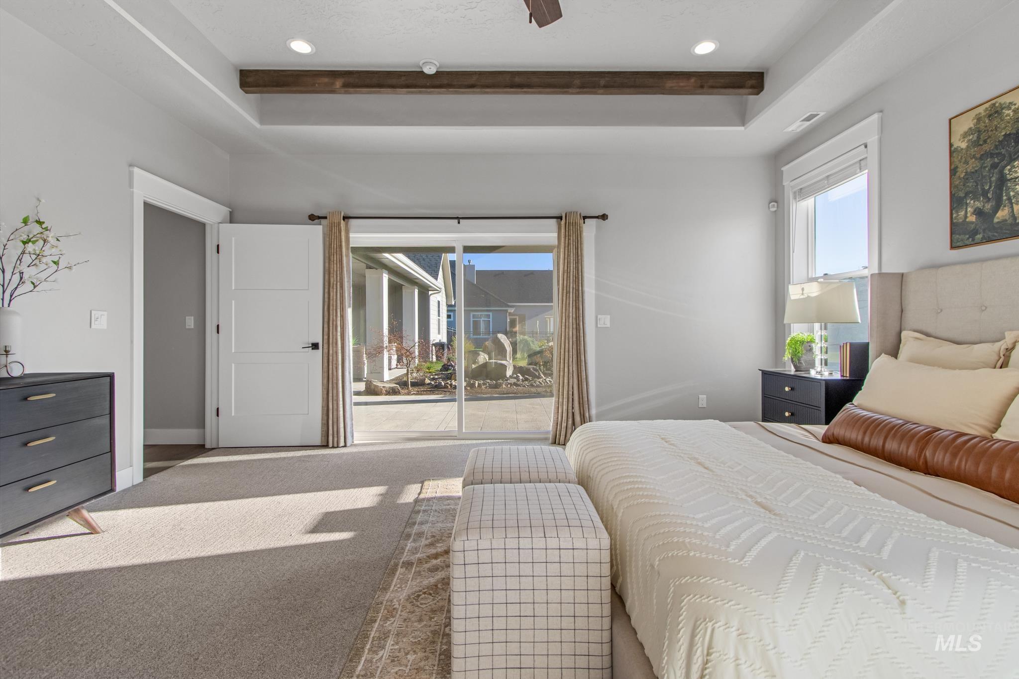 Bedroom with access to outside, carpet floors, a tray ceiling, ceiling fan, and multiple windows