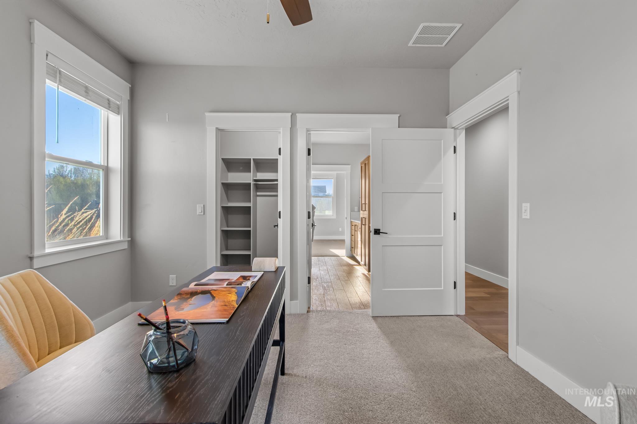Home office with light colored carpet and a ceiling fan