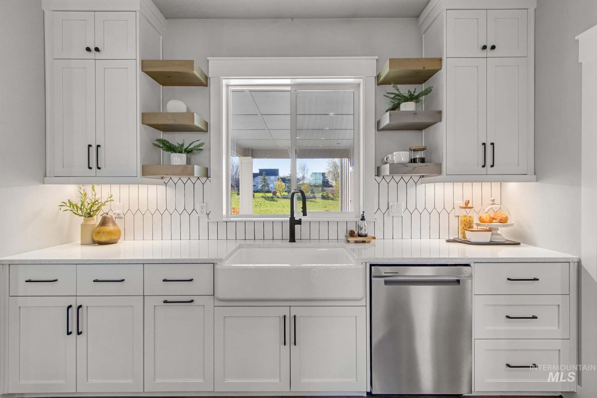 Kitchen with open shelves, stainless steel dishwasher, white cabinetry, and light stone countertops