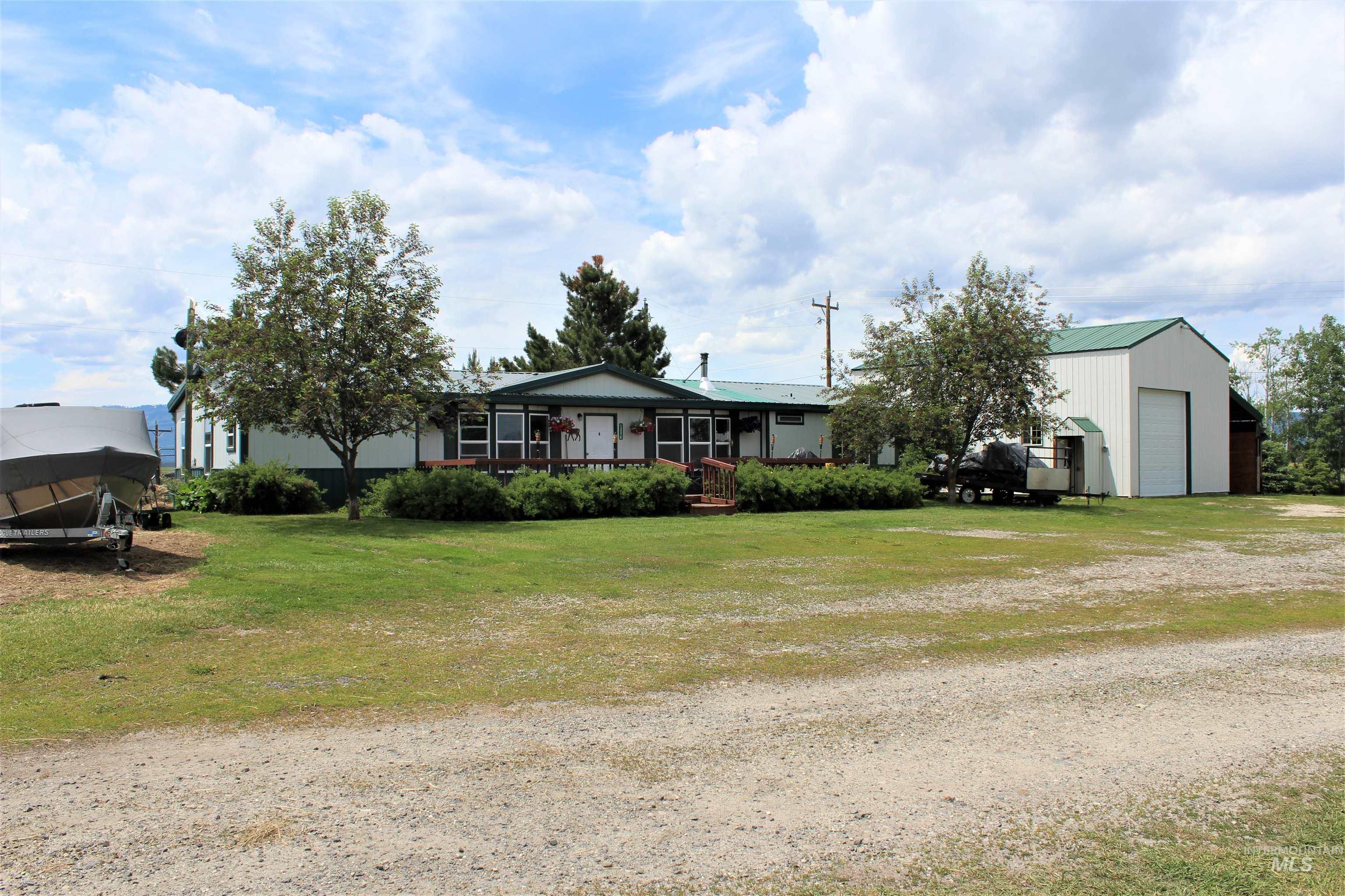 Back of property featuring a garage, a lawn, an outdoor structure, and driveway