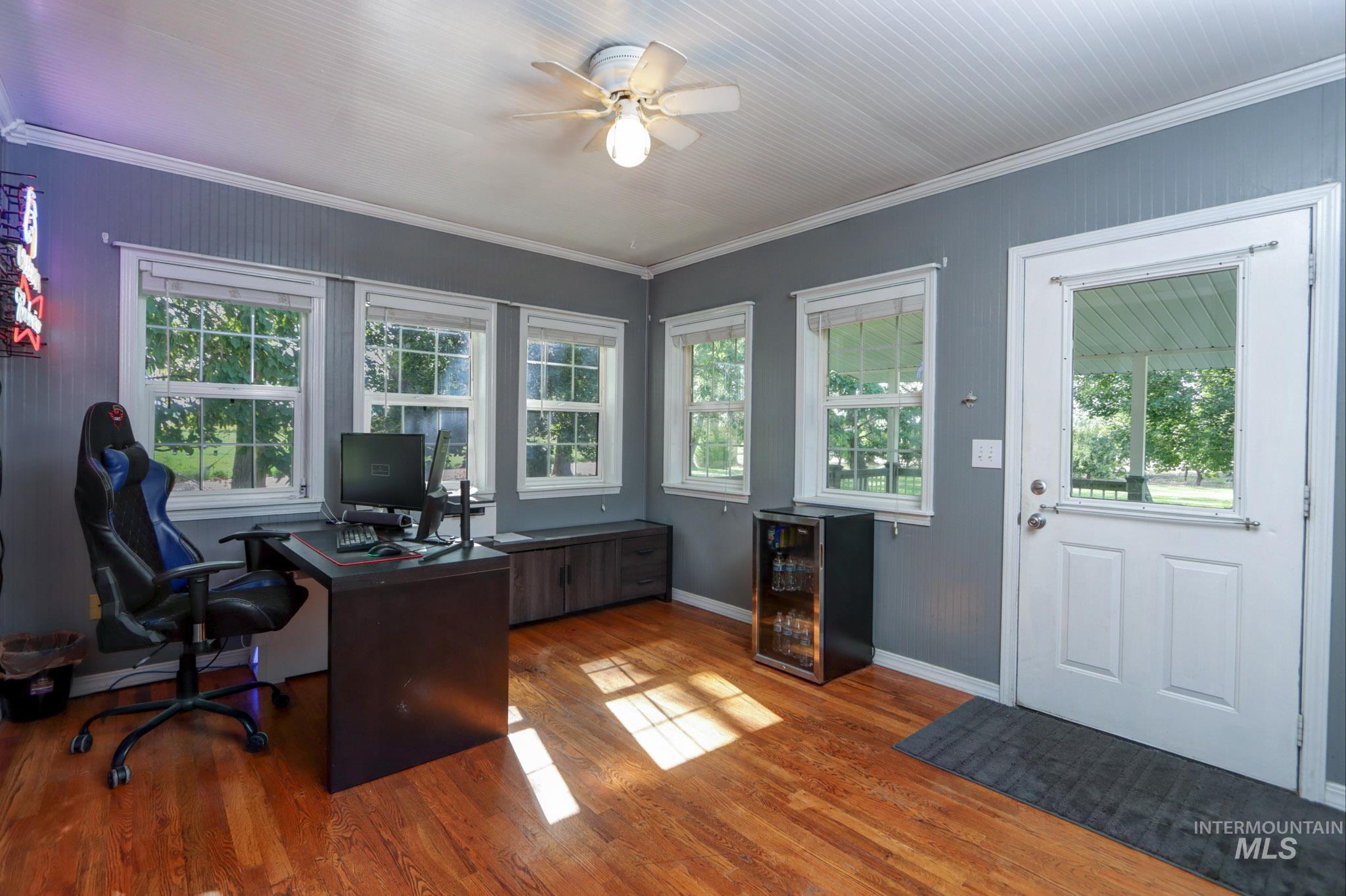 Office area featuring crown molding, light wood-style floors, plenty of natural light, and ceiling fan