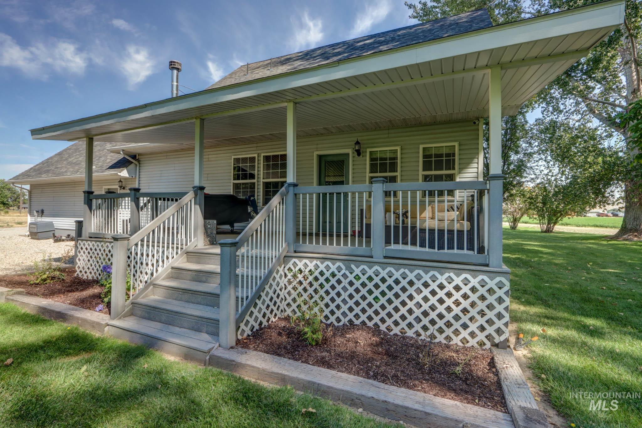 Property entrance with roof with shingles, a porch, and a yard
