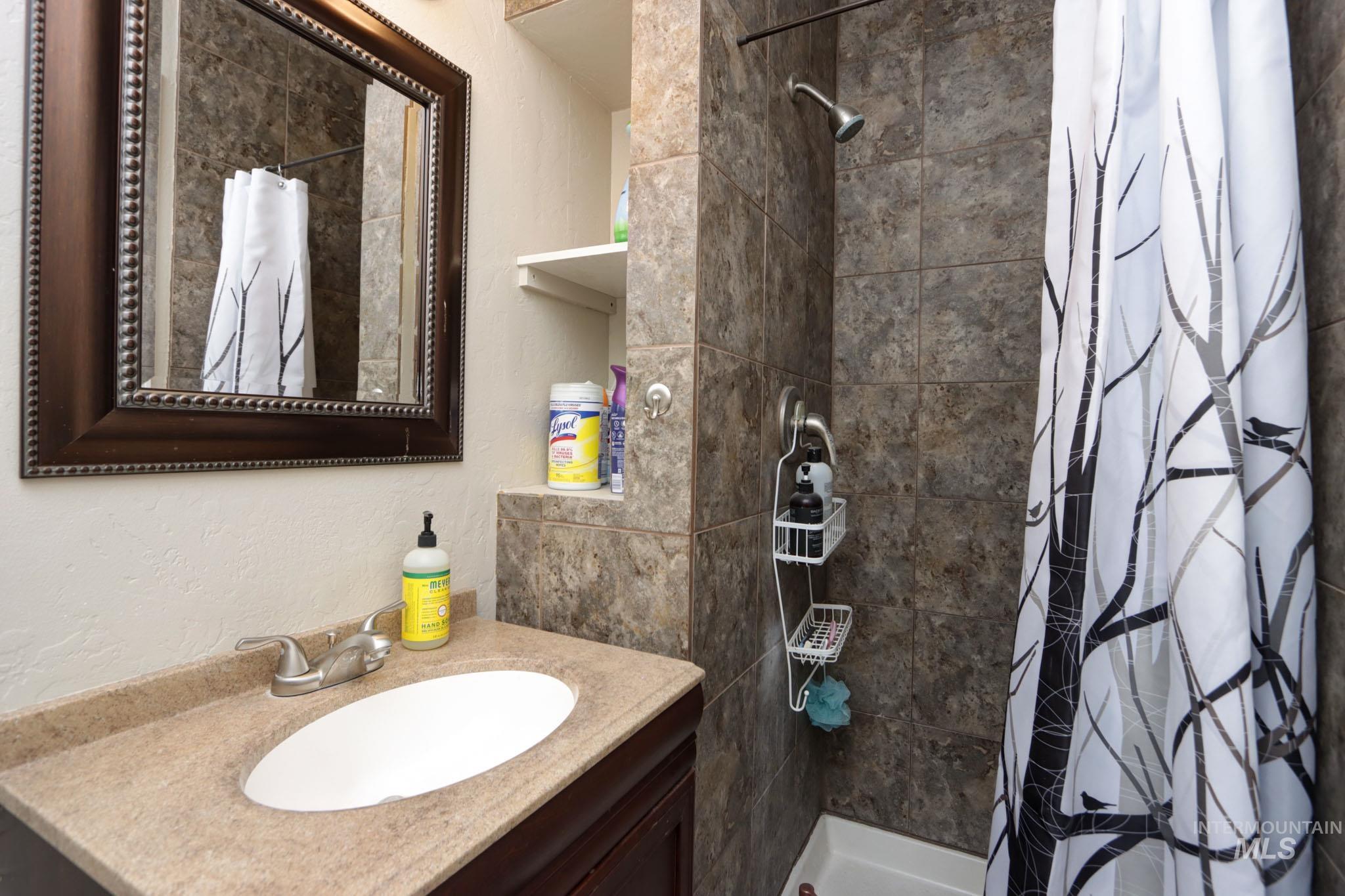 Full bath featuring a textured wall, vanity, and a stall shower