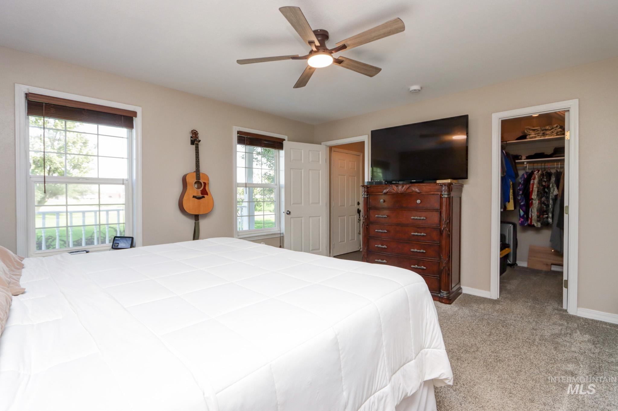 Bedroom featuring a walk in closet, light carpet, and a ceiling fan