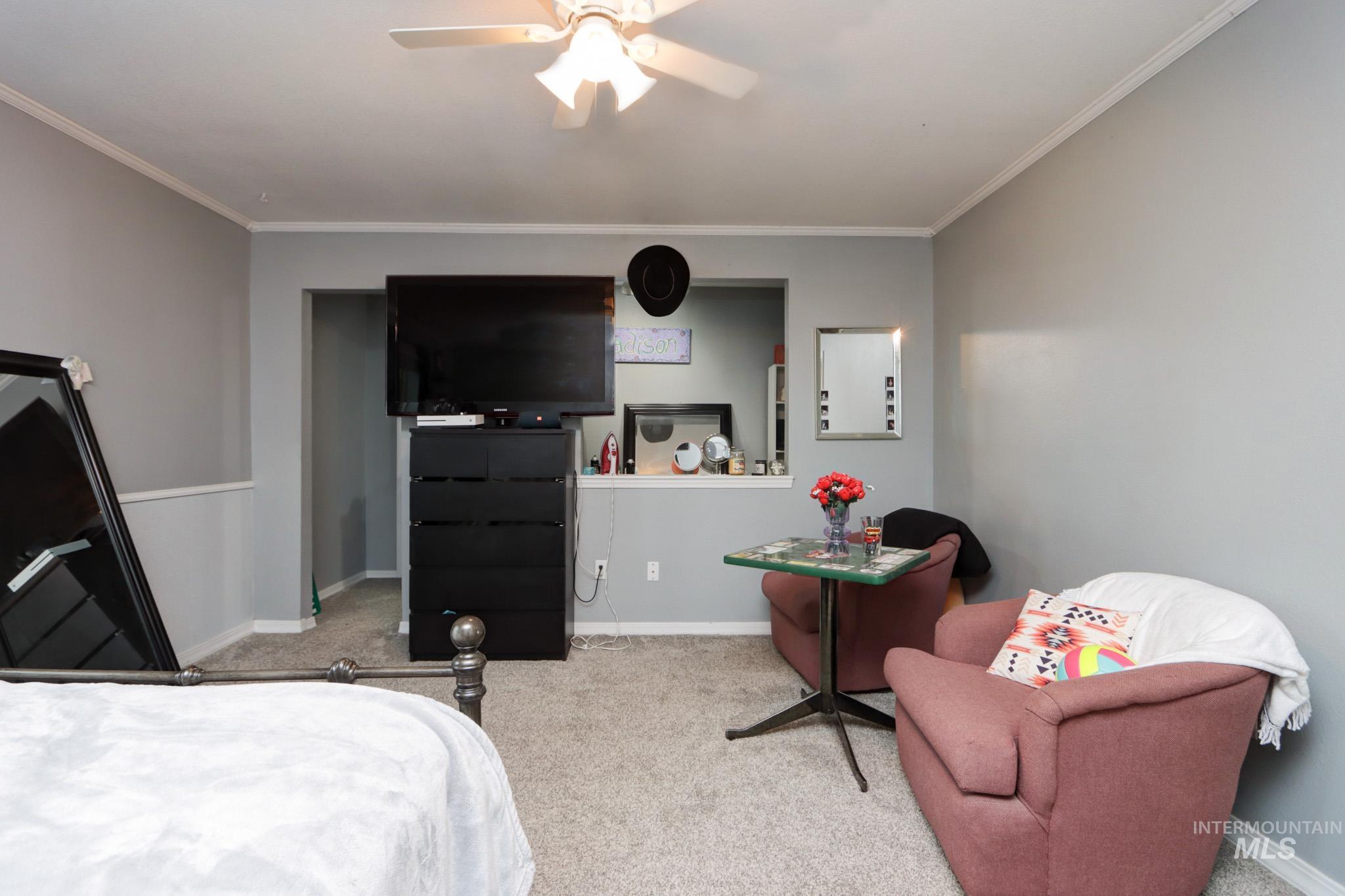 Bedroom with carpet, ornamental molding, and a ceiling fan