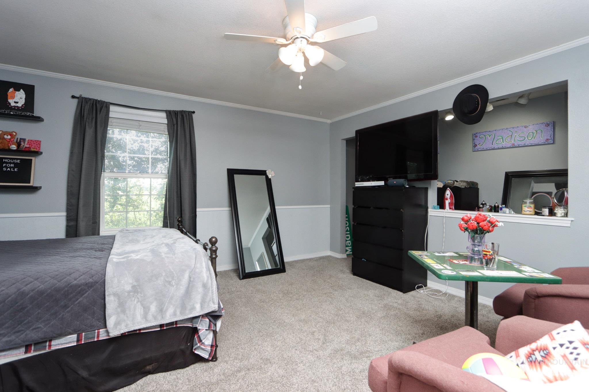 Carpeted bedroom featuring ornamental molding and a ceiling fan