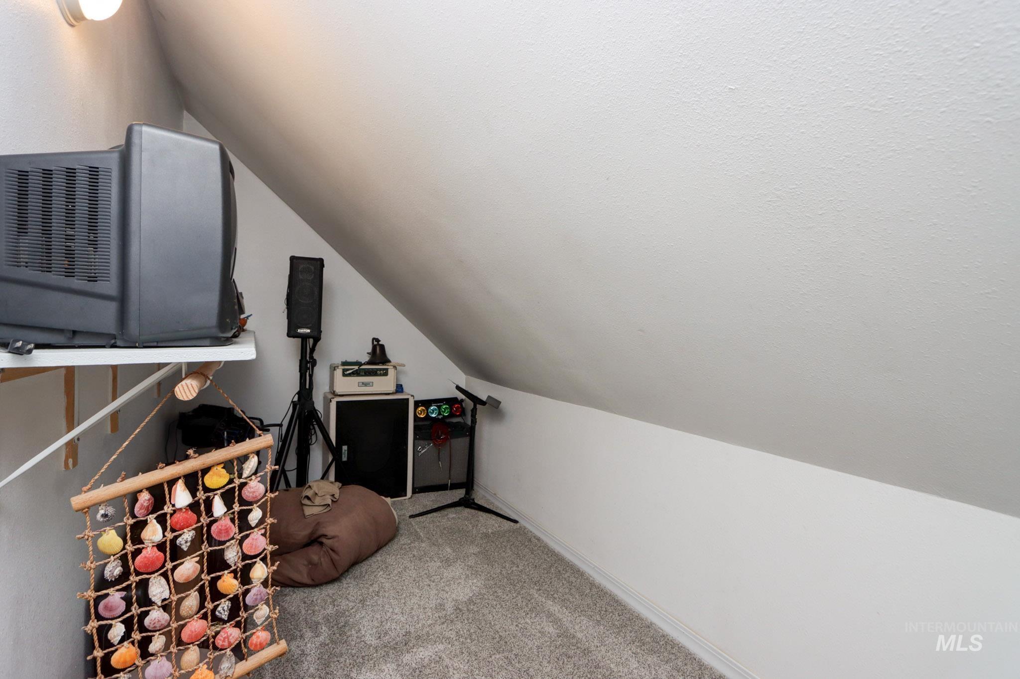 Recreation room with vaulted ceiling and light carpet