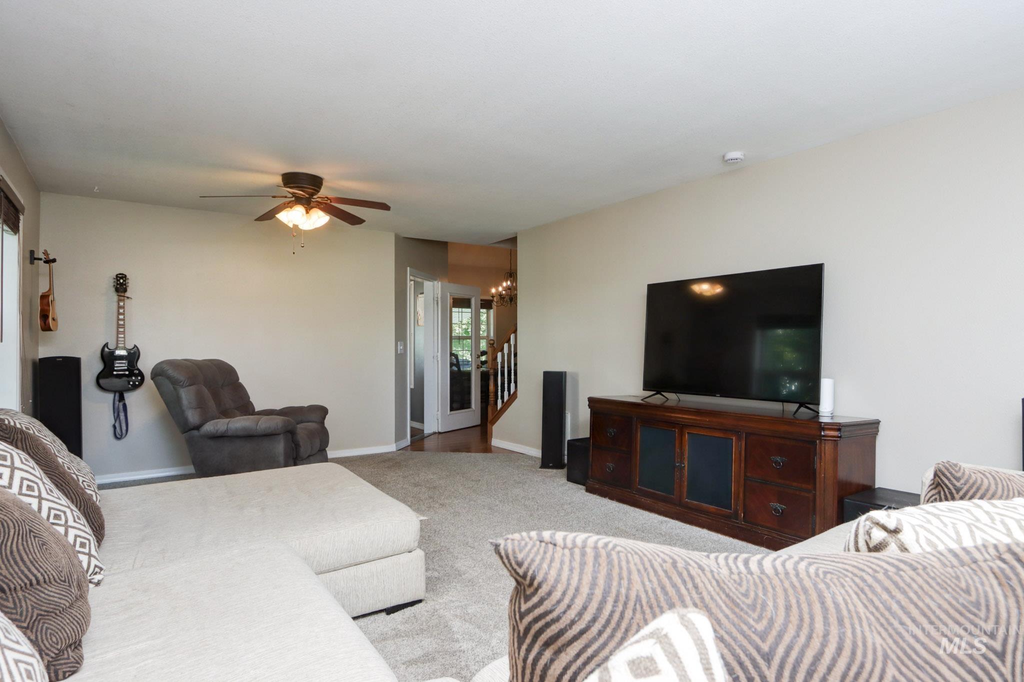 Living room with carpet flooring, a chandelier, and a ceiling fan