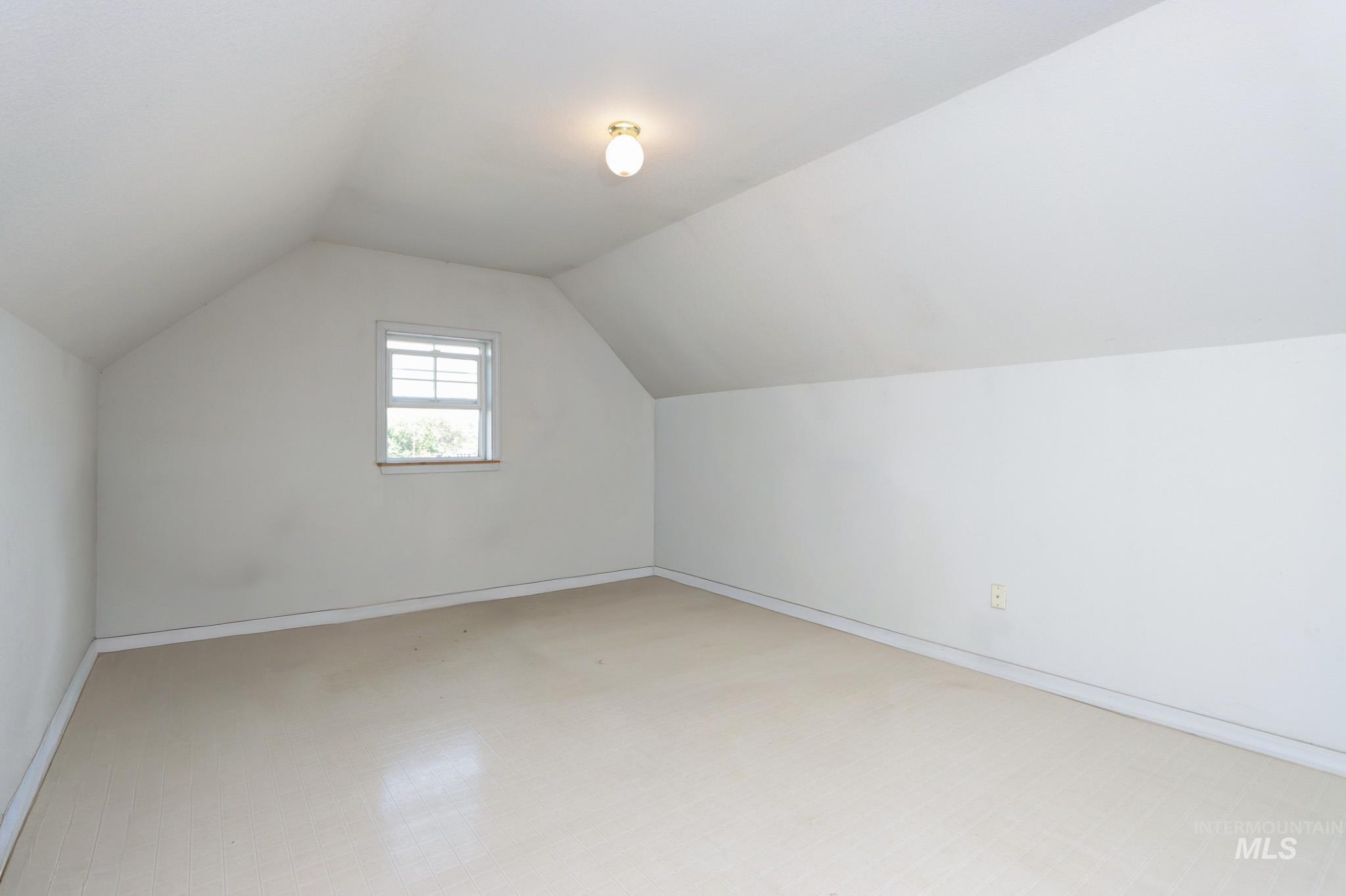 Additional living space with vaulted ceiling and baseboards