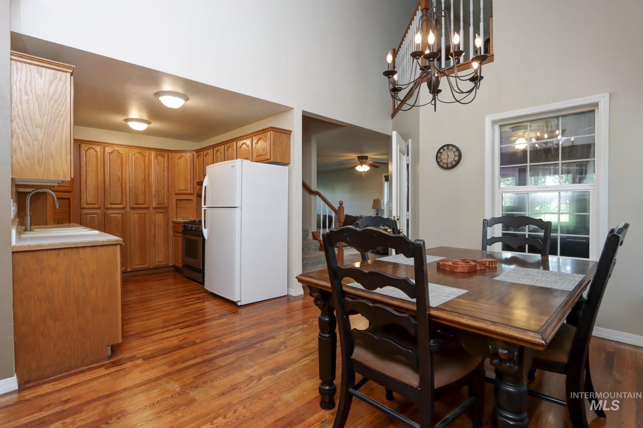 Dining room featuring a chandelier, dark wood-type flooring, stairway, ceiling fan, and a high ceiling