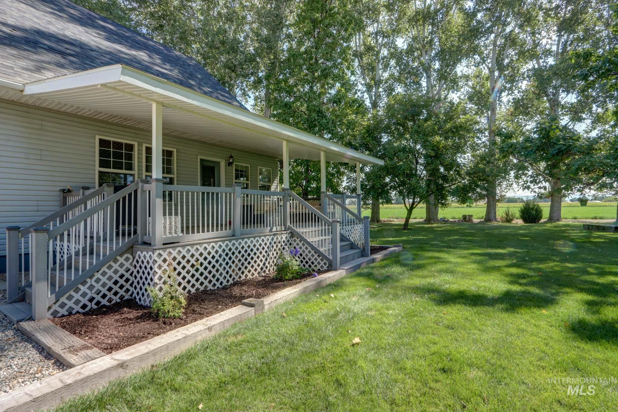 View of green lawn featuring covered porch and stairs
