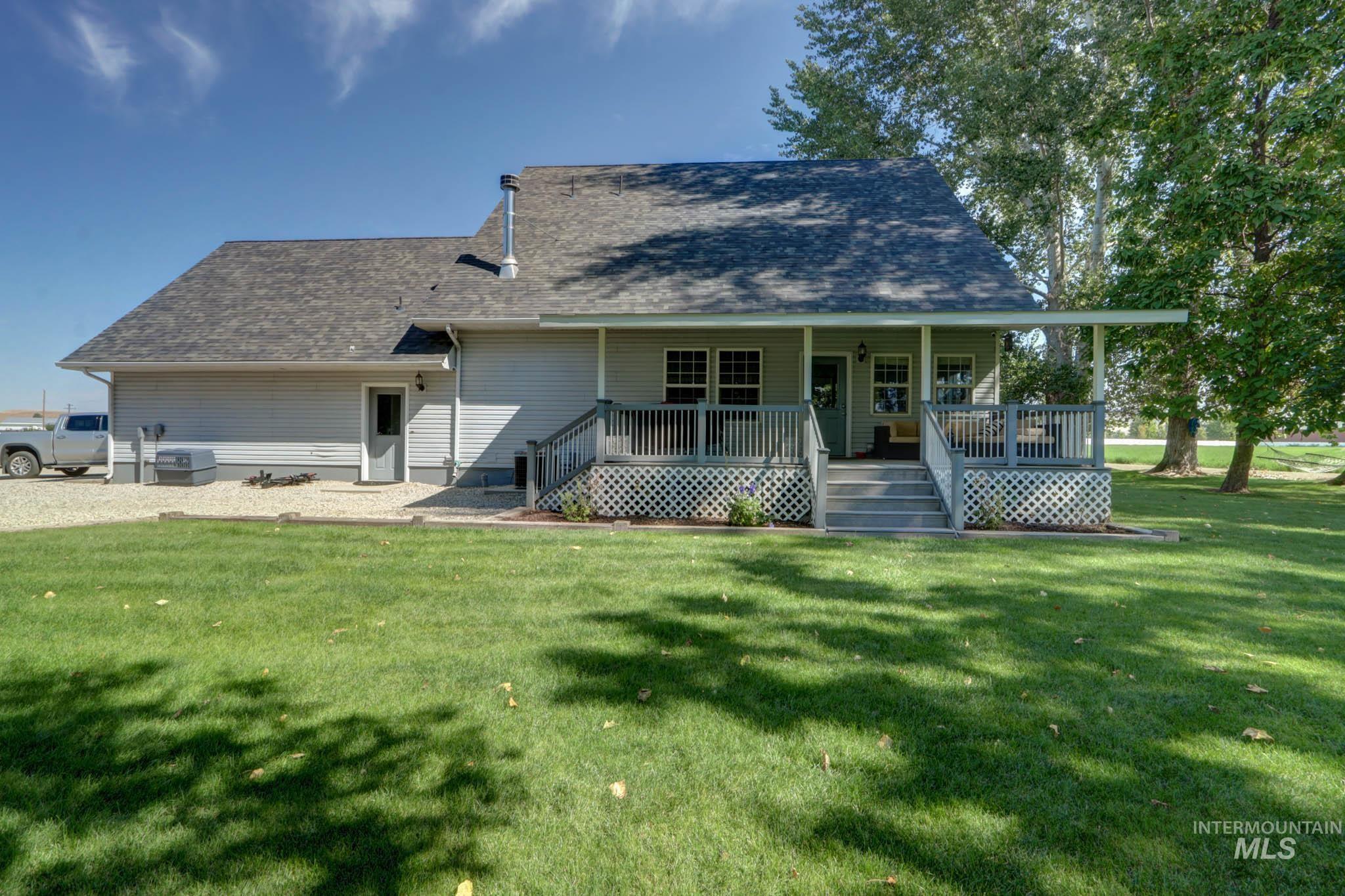 Back of house featuring covered porch, roof with shingles, a lawn, and stairs