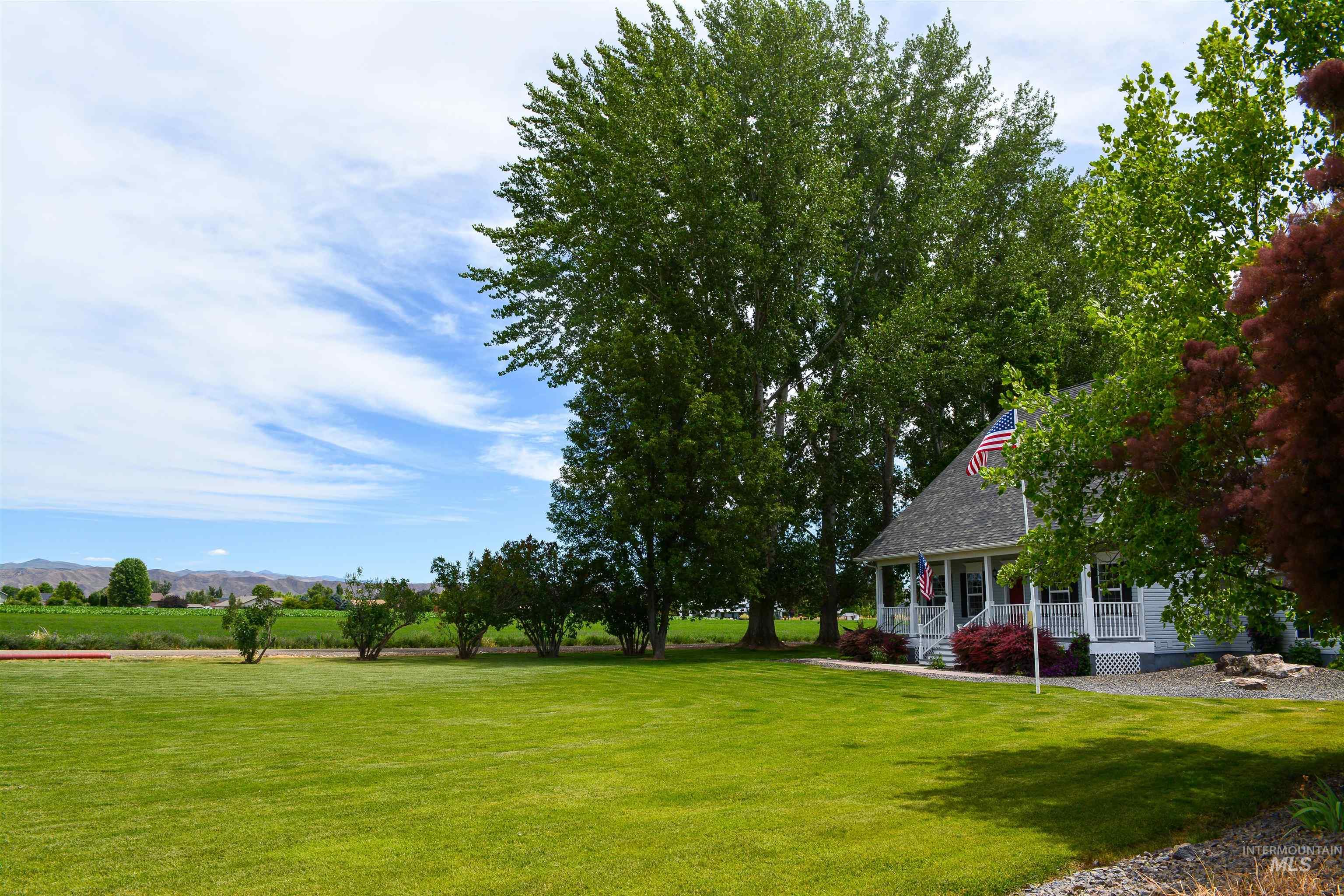 View of grassy yard featuring a porch, a view of rural / pastoral area, and a mountain view