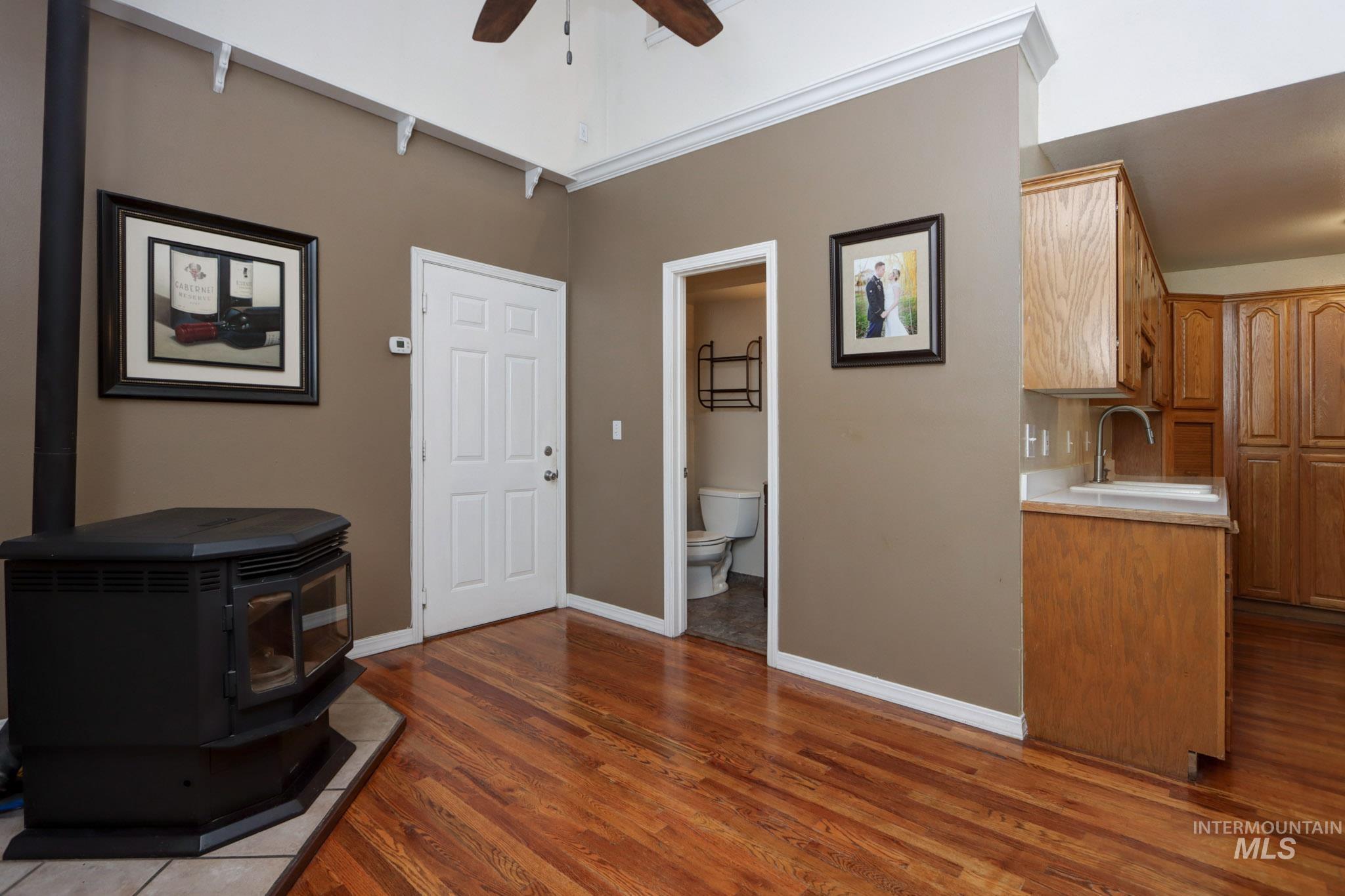 Living room featuring a wood stove, dark wood-style floors, and ceiling fan