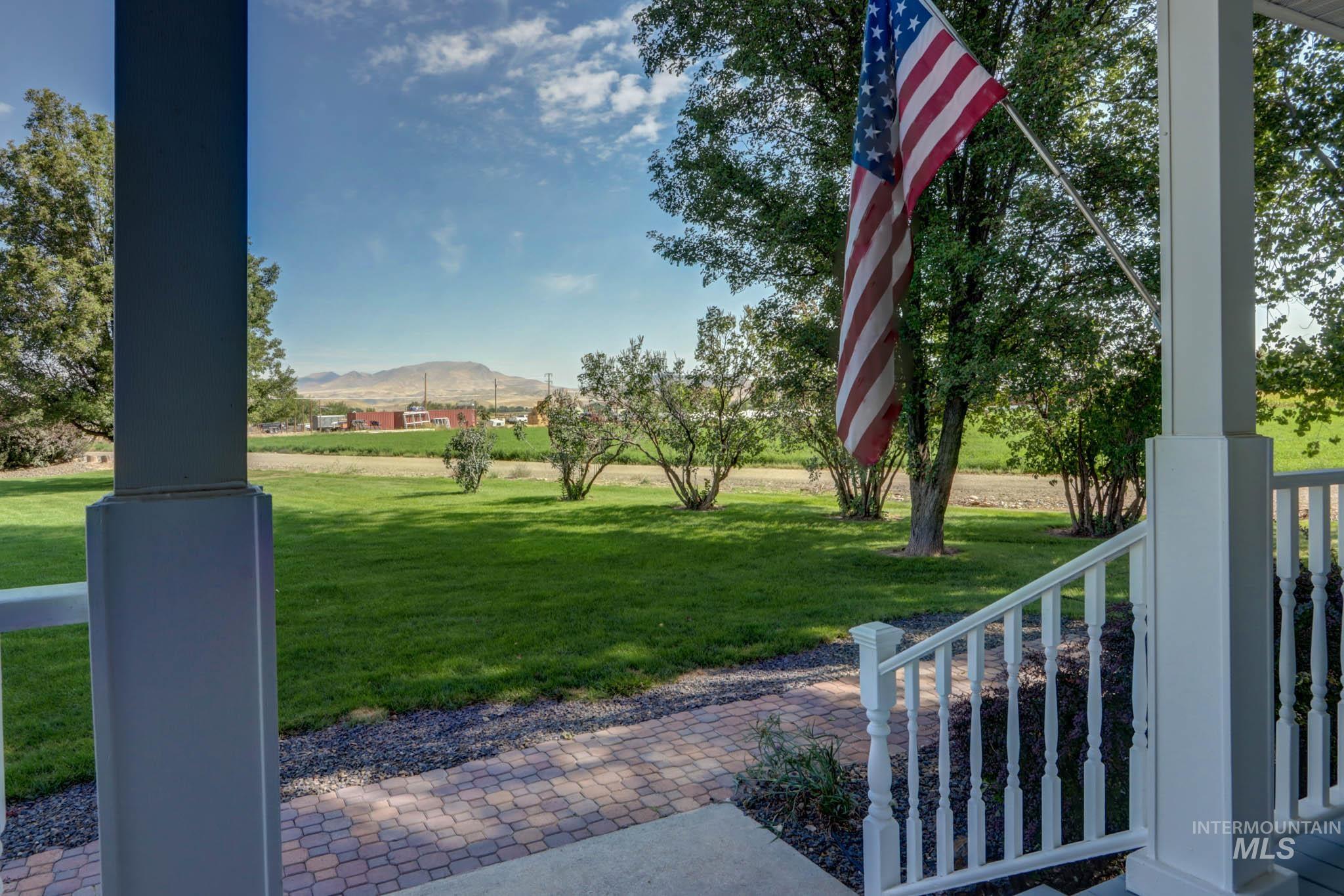 View of green lawn with a mountain view and a porch