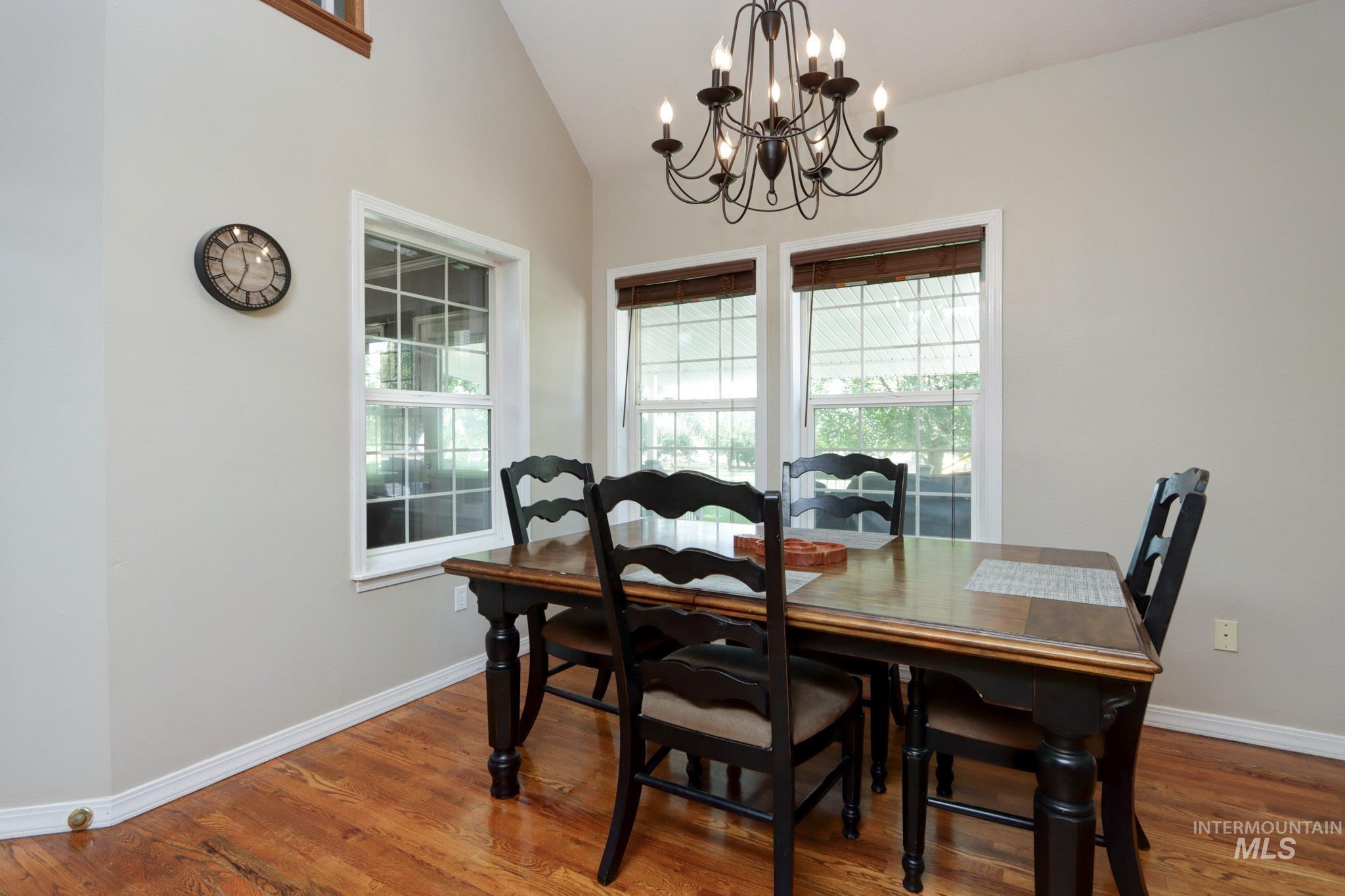 Dining room with plenty of natural light, lofted ceiling, wood finished floors, and a chandelier