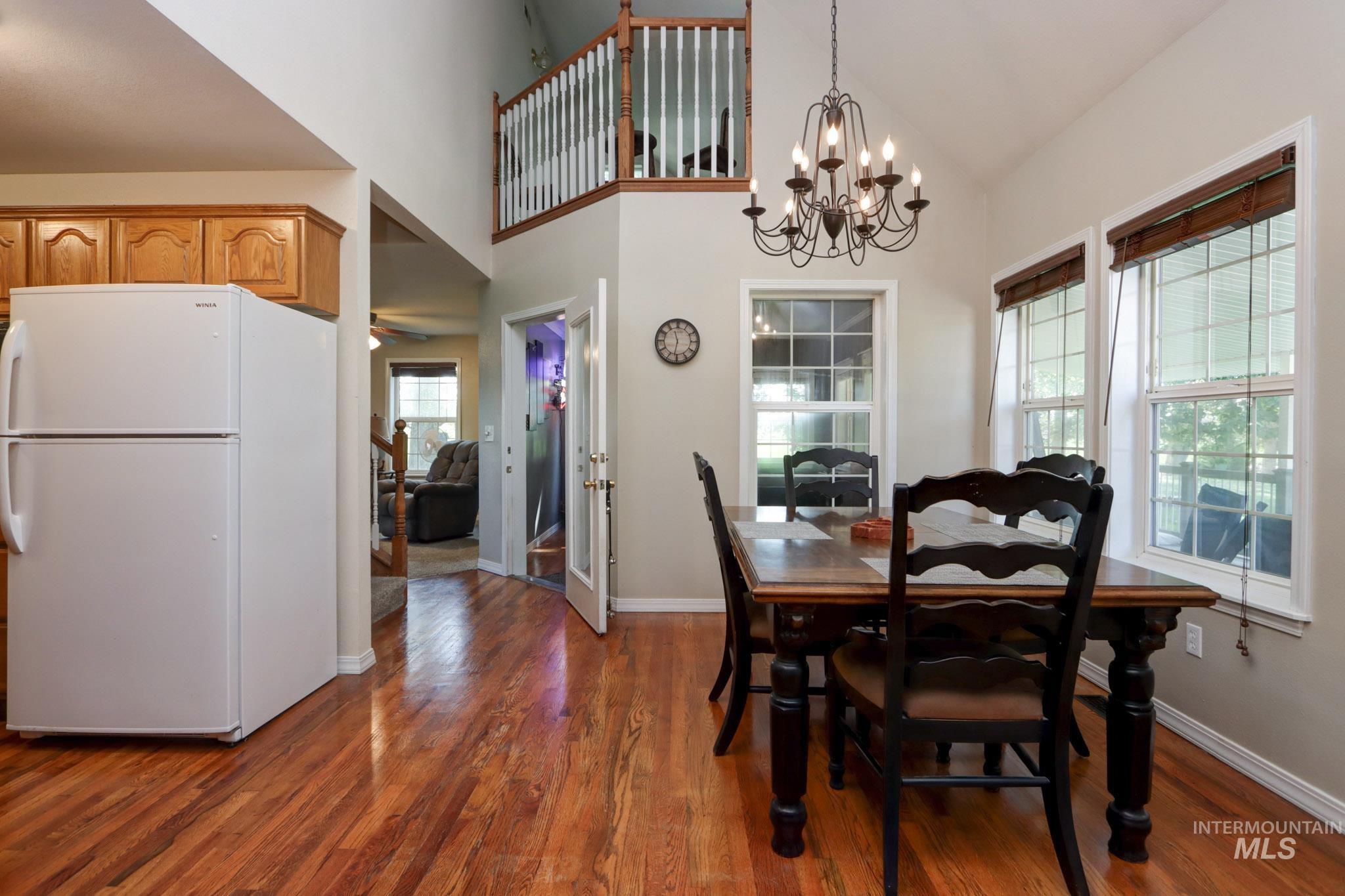 Dining room featuring dark wood finished floors, high vaulted ceiling, and a chandelier