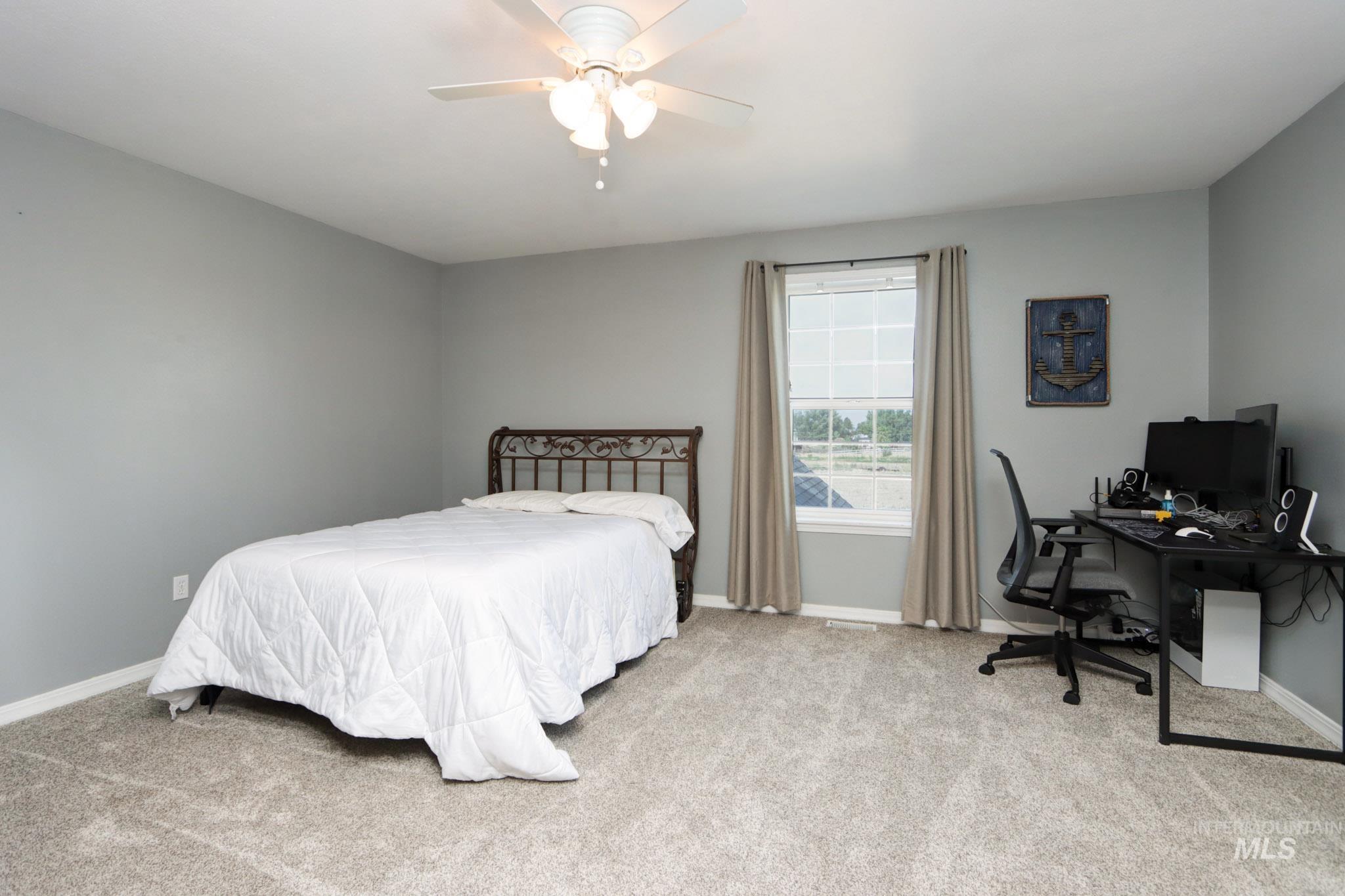 Bedroom featuring light carpet, an office area, and ceiling fan