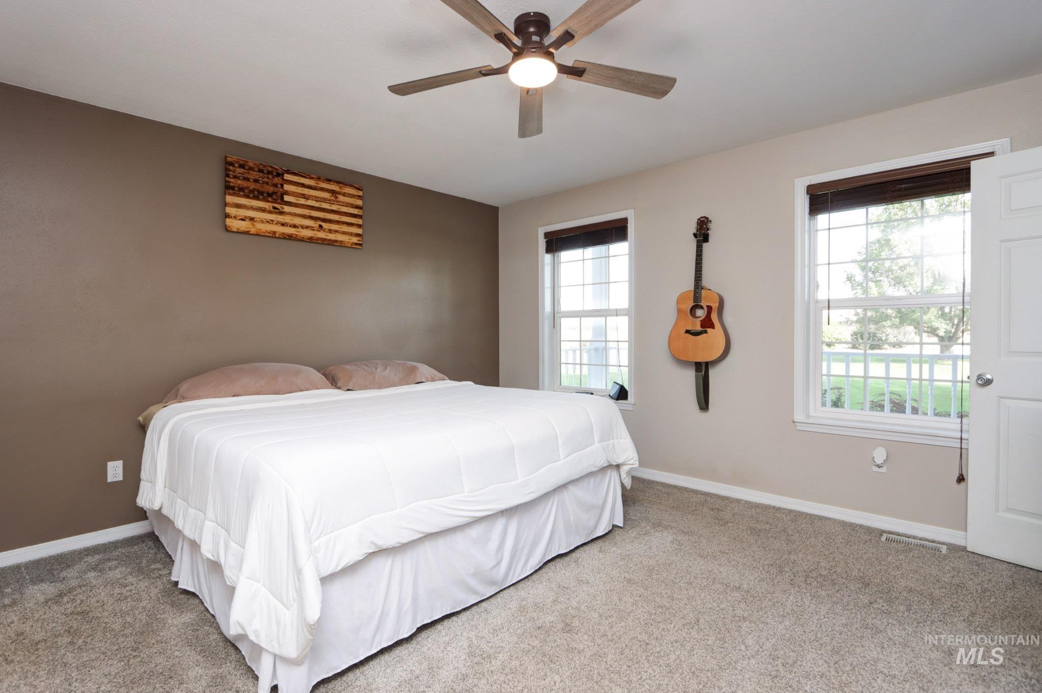 Carpeted bedroom featuring ceiling fan and baseboards