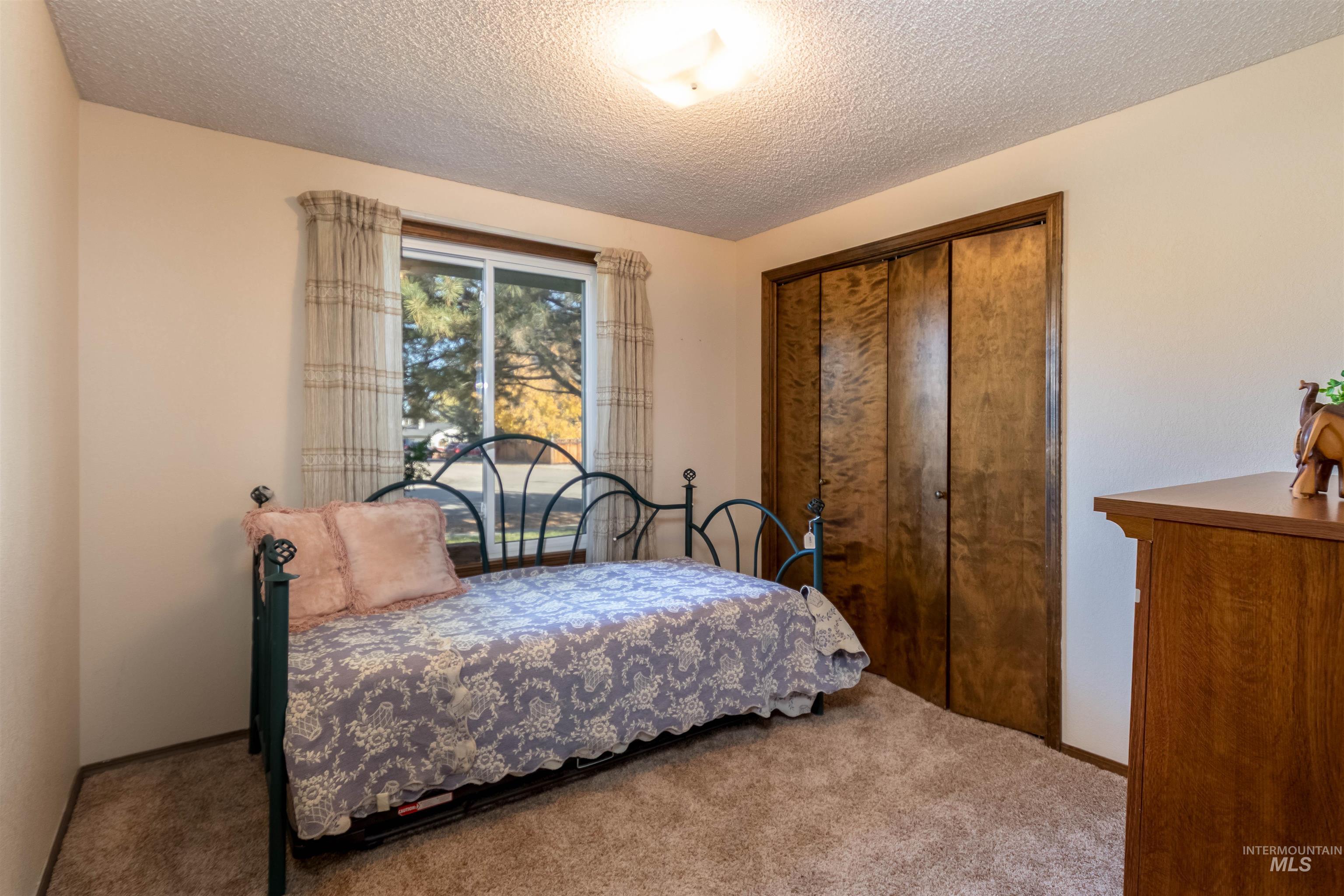 Bedroom with carpet floors, a closet, and a textured ceiling