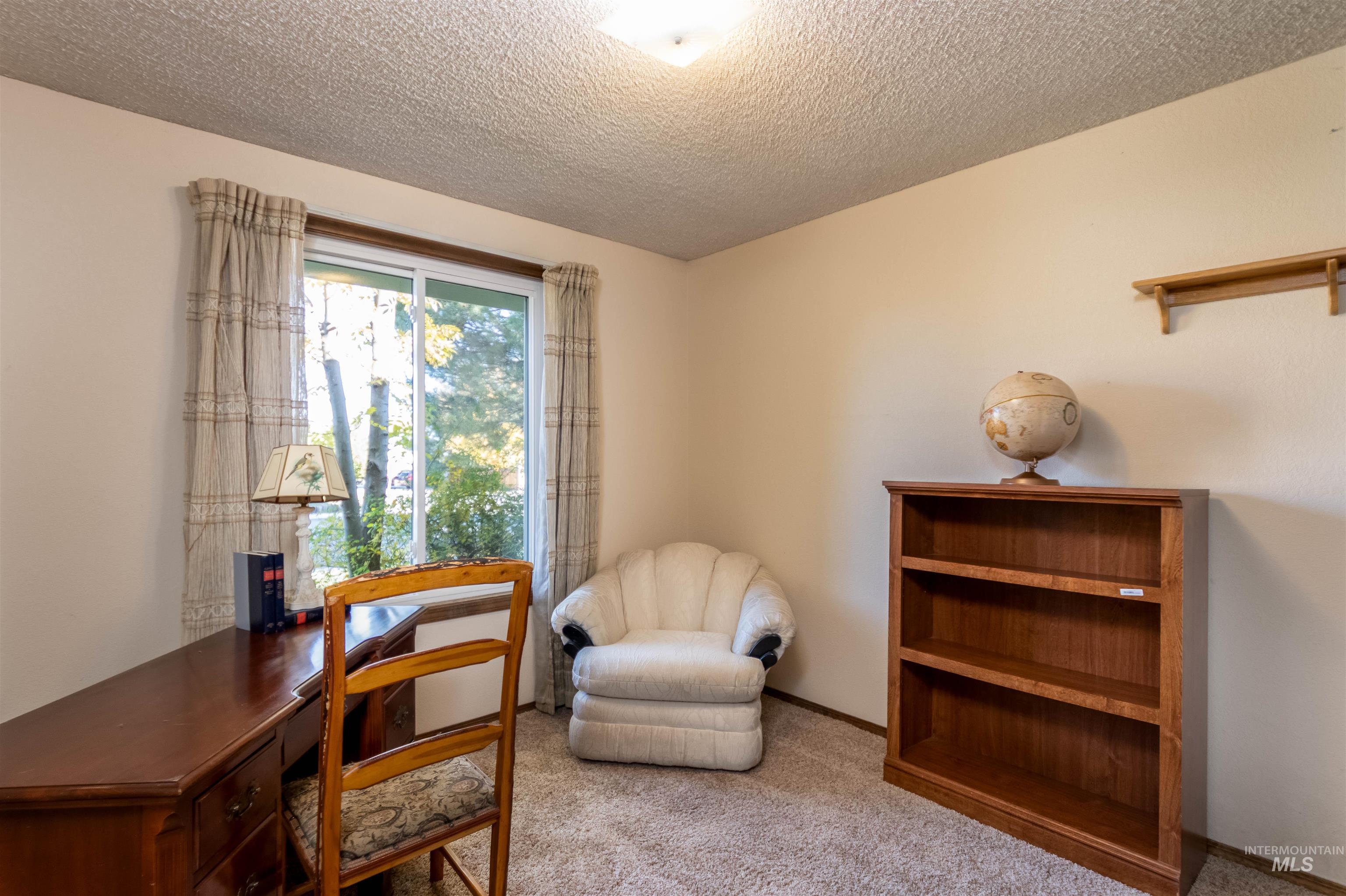 Sitting room featuring carpet flooring, an office area, and a textured ceiling