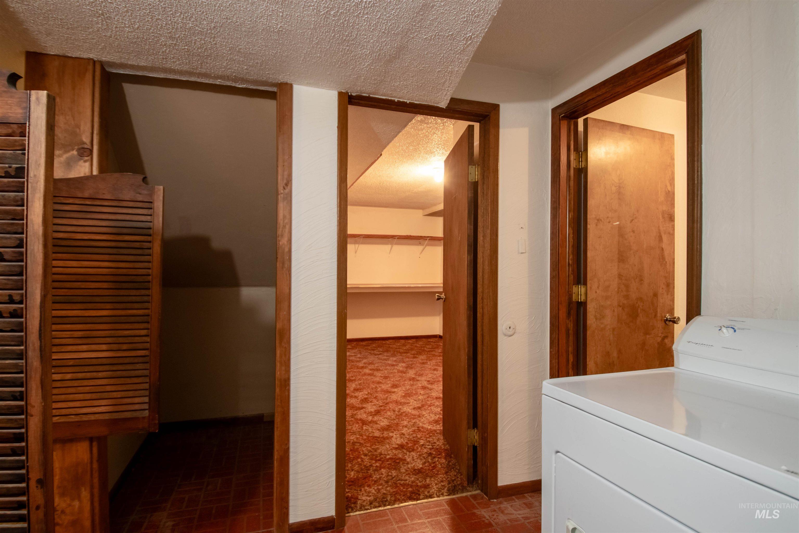 Washroom with washer / clothes dryer, a textured ceiling, and brick patterned flooring