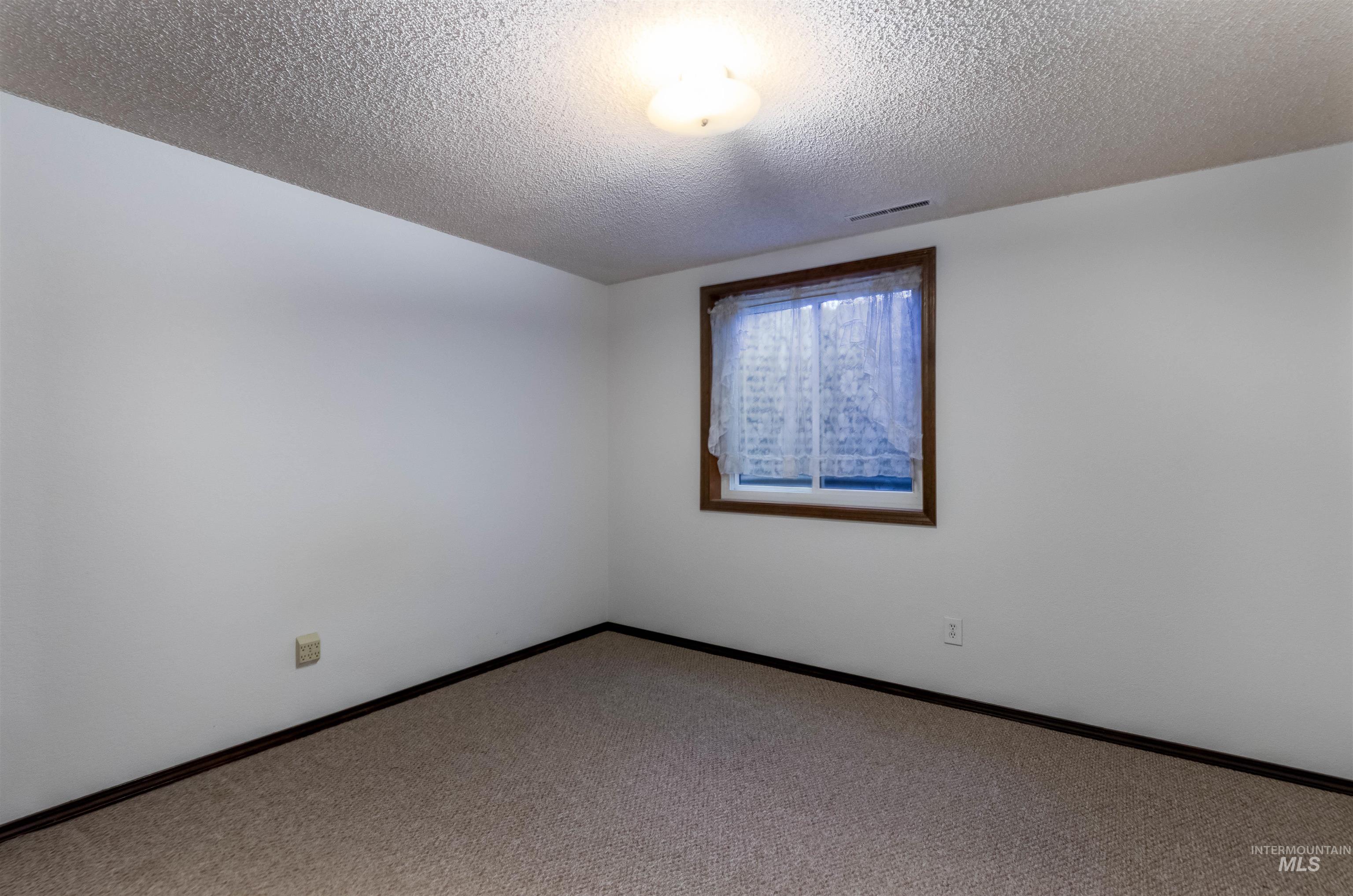 Empty room featuring carpet floors and a textured ceiling