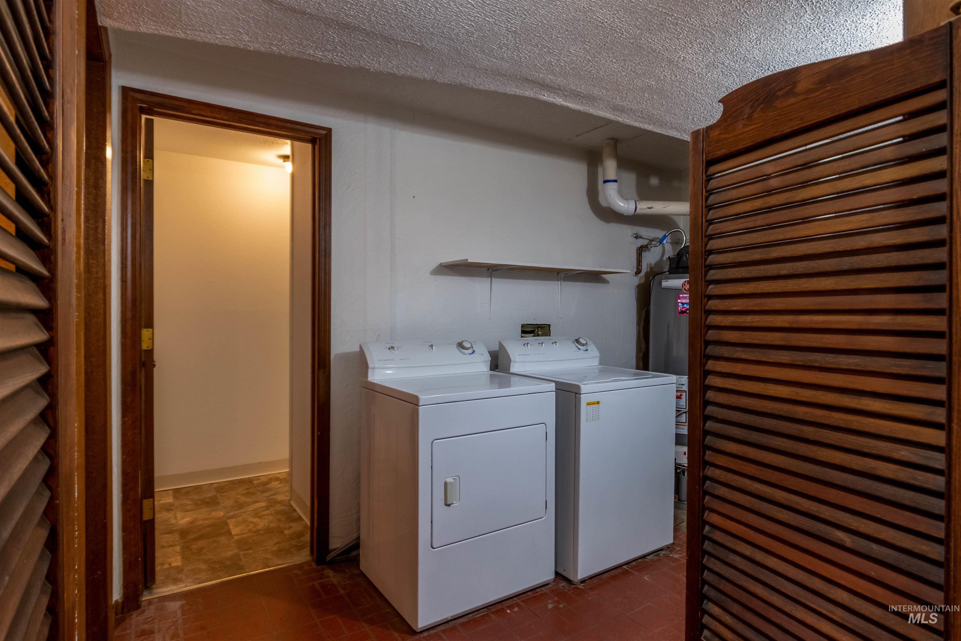 Laundry area featuring washing machine and dryer, a textured ceiling, and gas water heater
