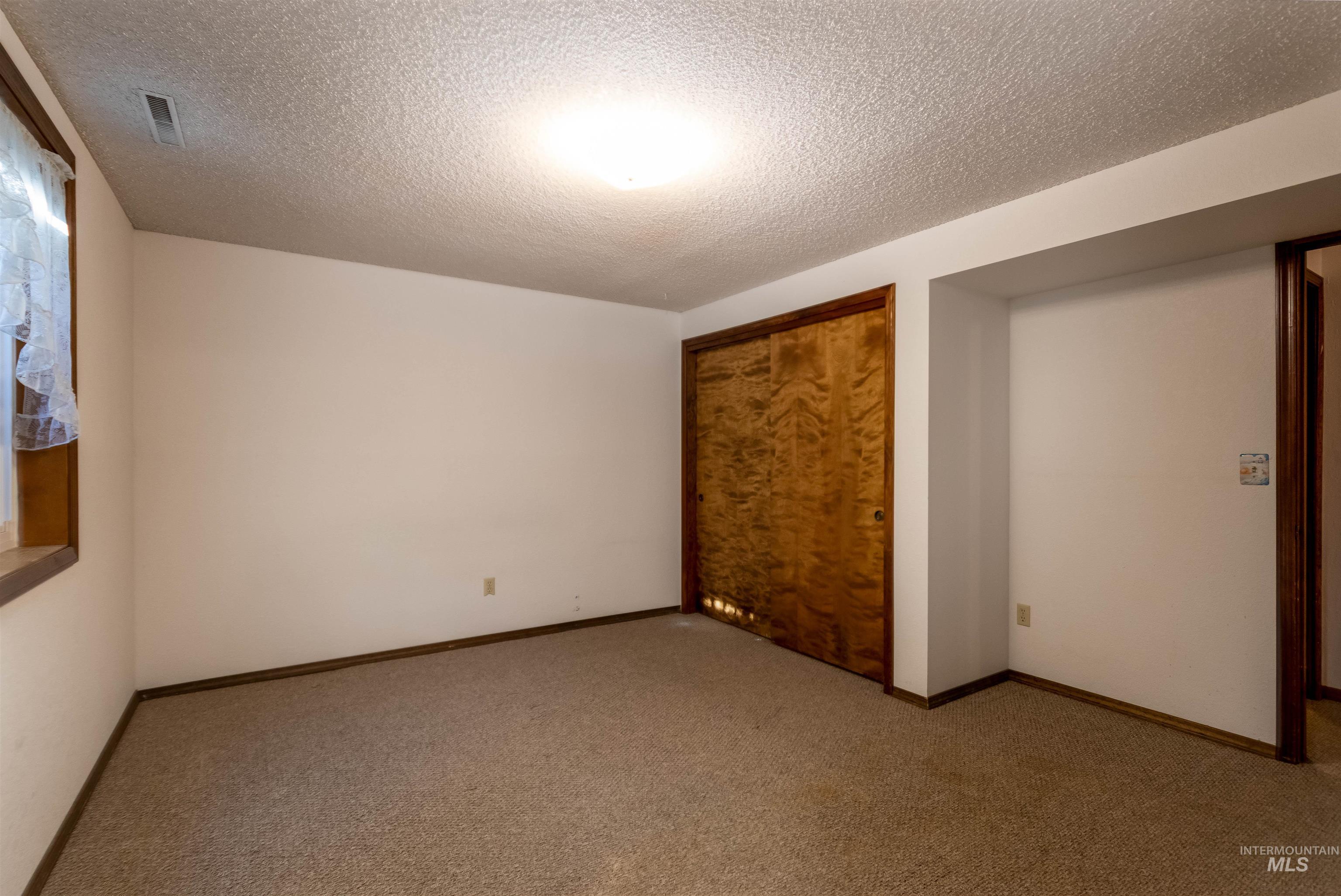 Unfurnished bedroom featuring a textured ceiling, carpet, and a closet