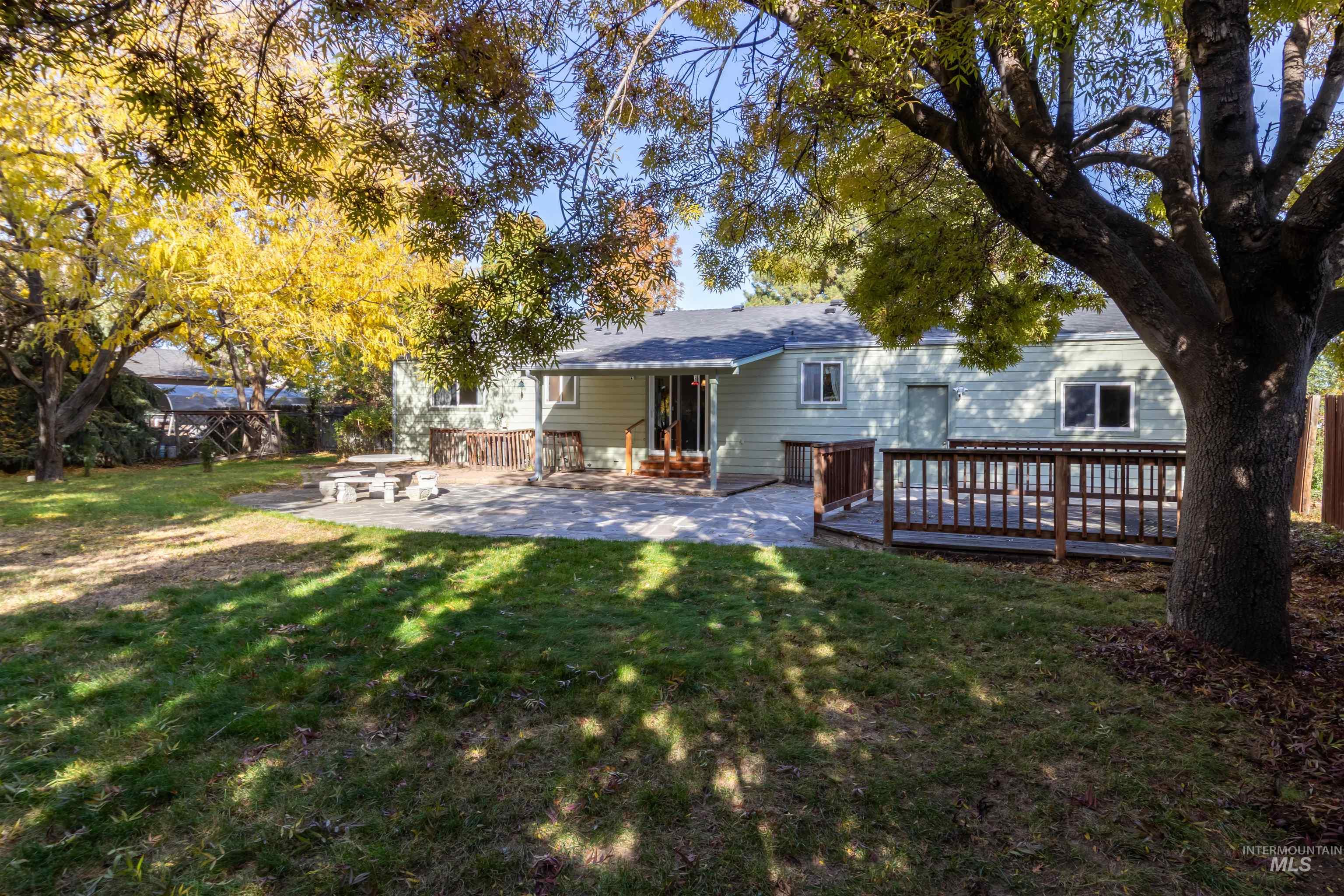 Back of house featuring a lawn, a patio, and a wooden deck