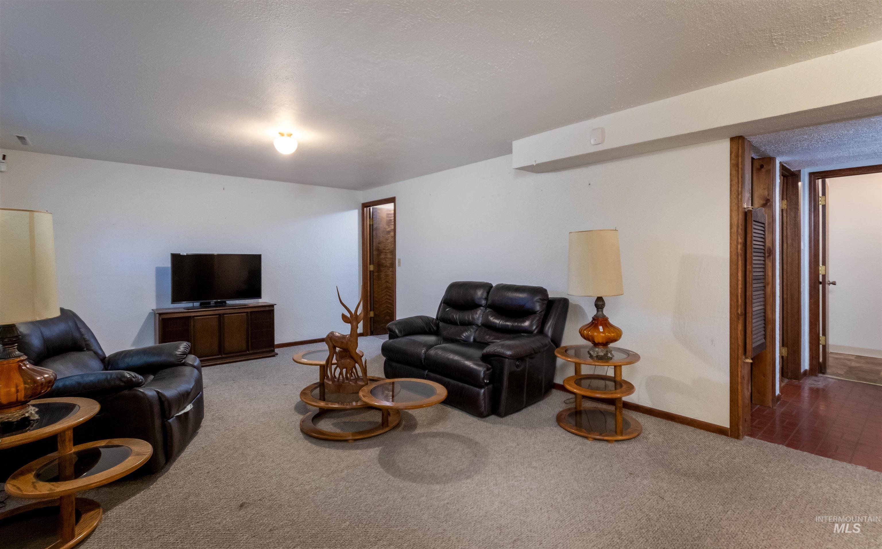 Carpeted living area with baseboards and a textured ceiling