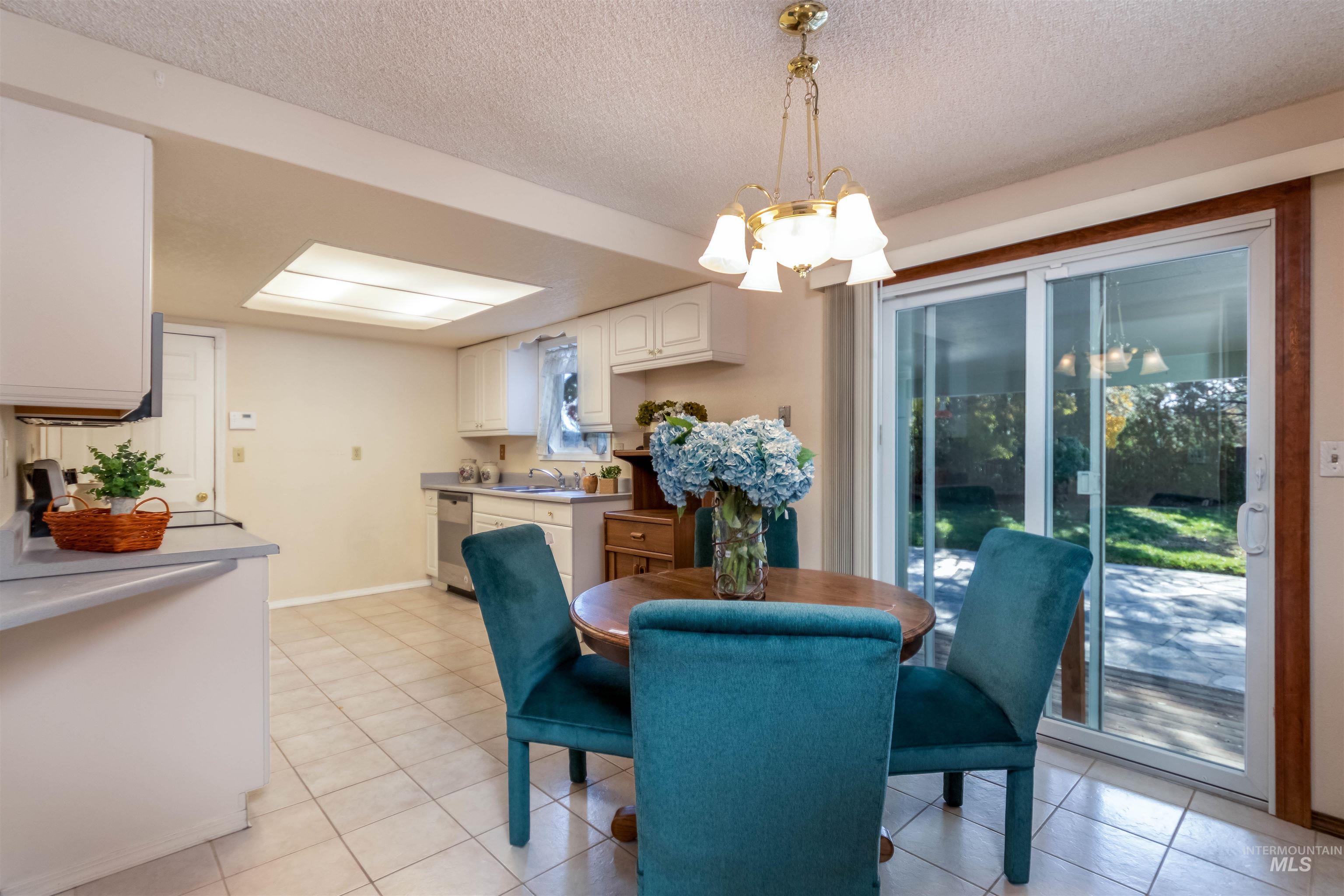 Dining area with a chandelier, light tile patterned floors, and a textured ceiling