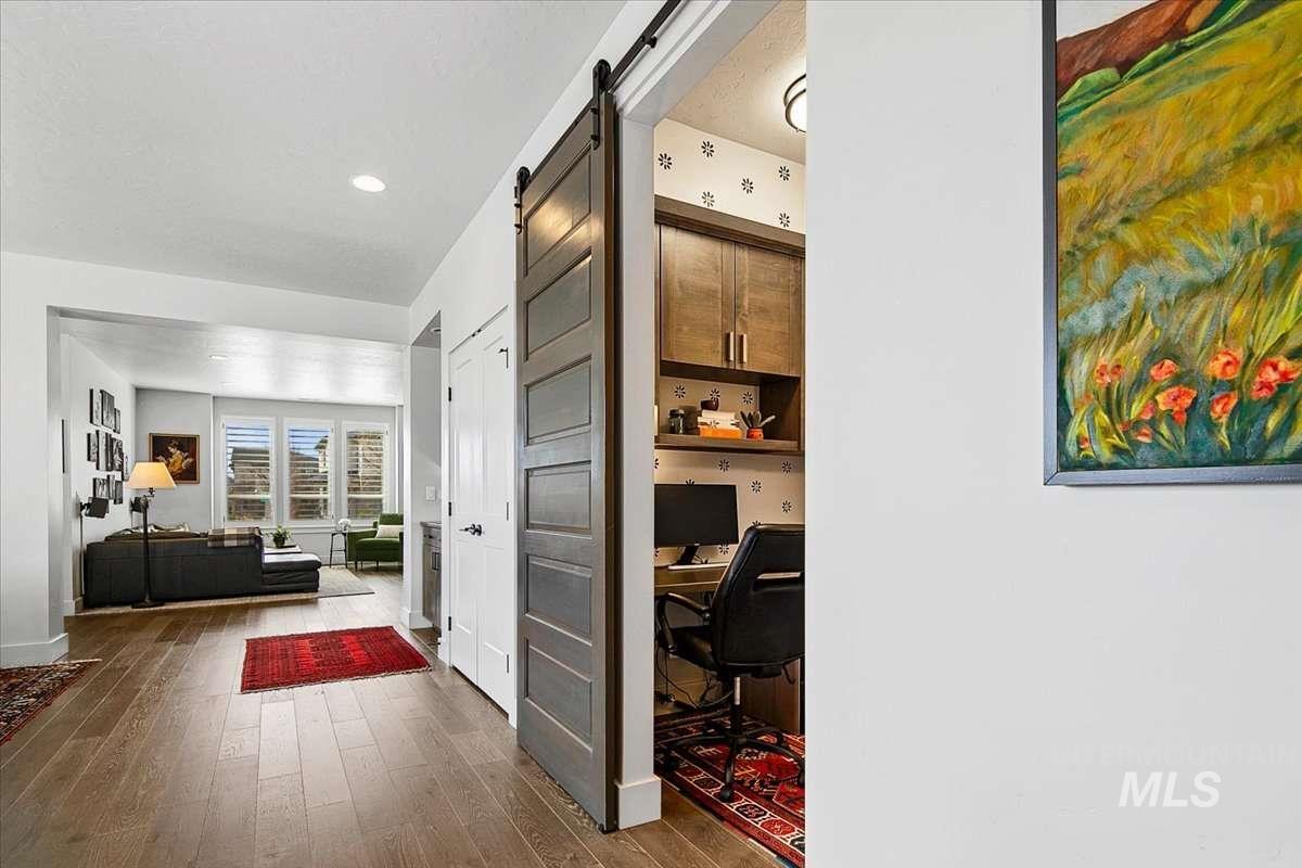 Hallway featuring an office area, a barn door, dark wood-style floors, and recessed lighting