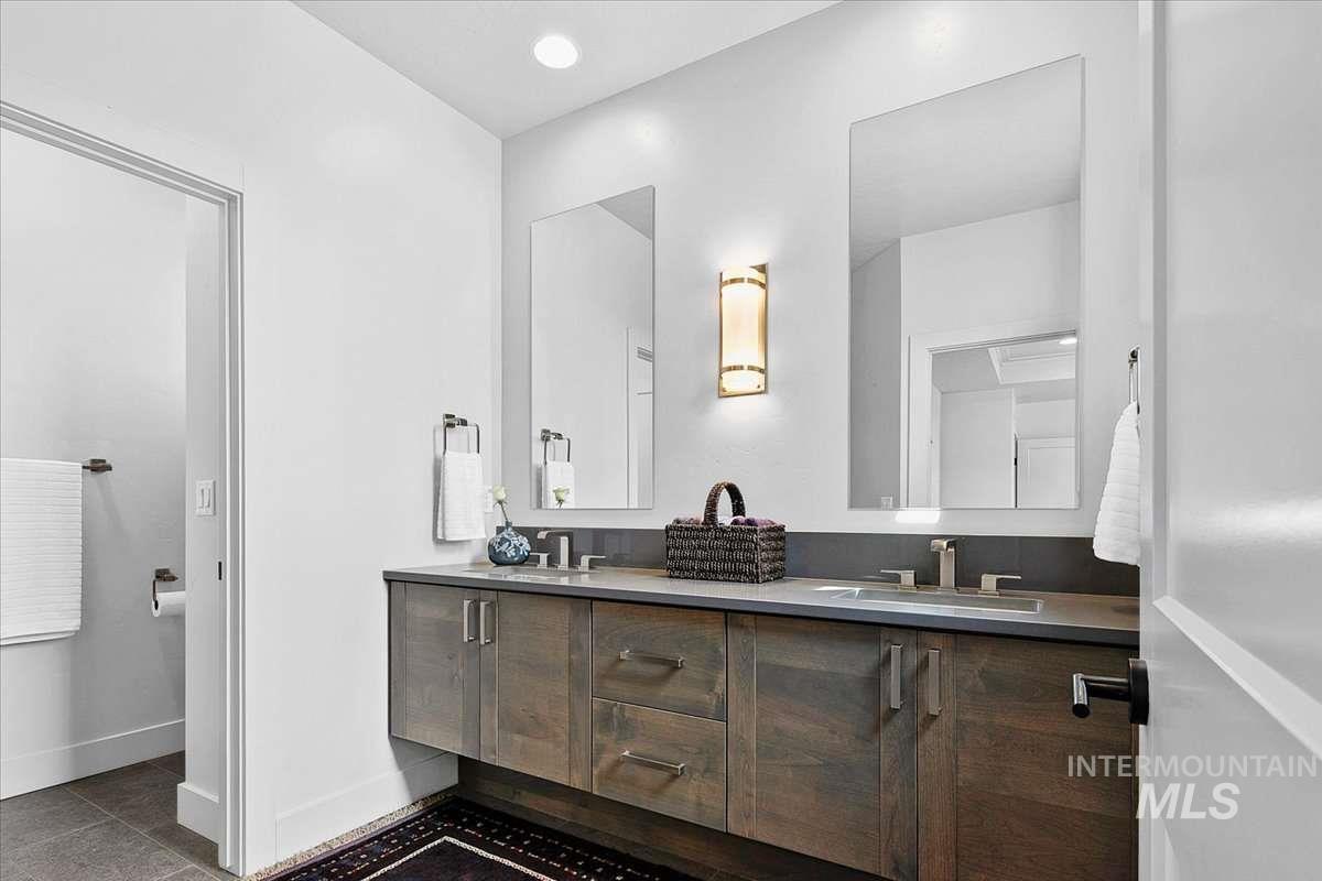 Full bathroom featuring double vanity and baseboards