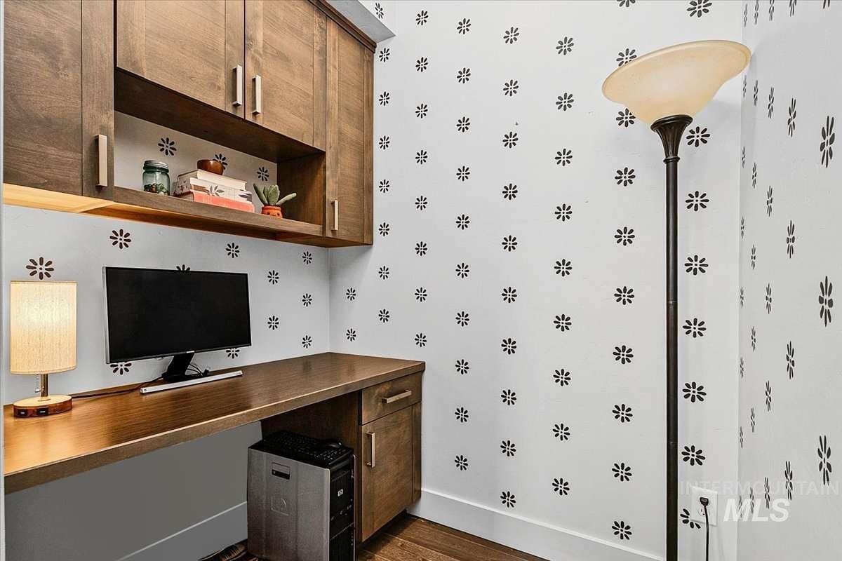 Bar with dark wood-style flooring, built in desk, and dark wood finish cabinetry
