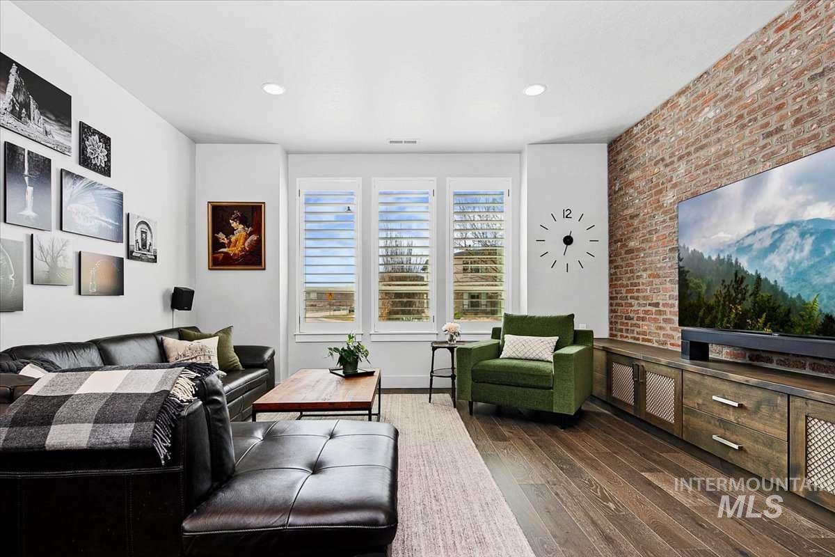 Living area with brick wall, dark wood finished floors, and recessed lighting