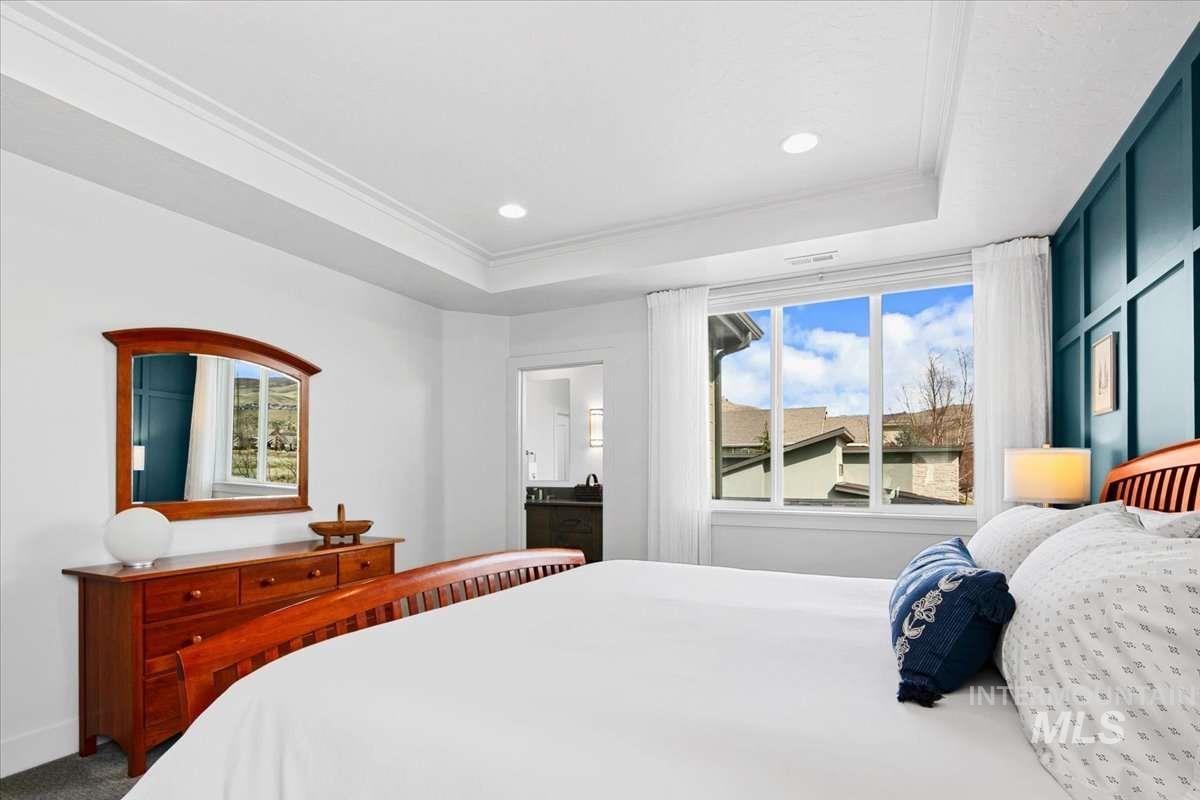 Carpeted bedroom with crown molding, recessed lighting, and a tray ceiling