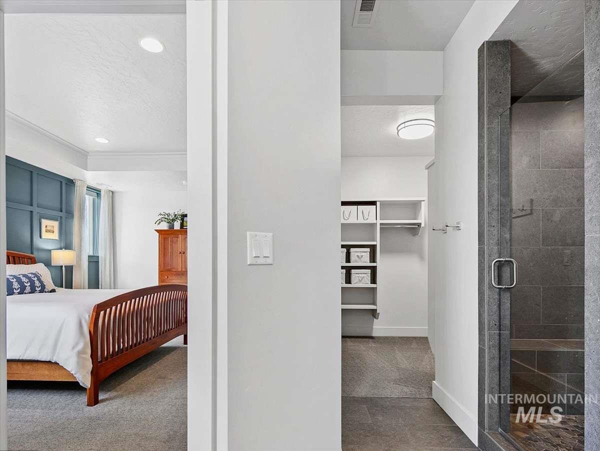 Bedroom featuring a walk in closet, dark carpet, recessed lighting, and a textured ceiling