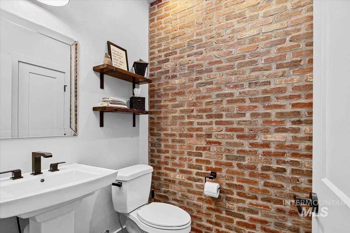 Half bathroom with brick wall and toilet