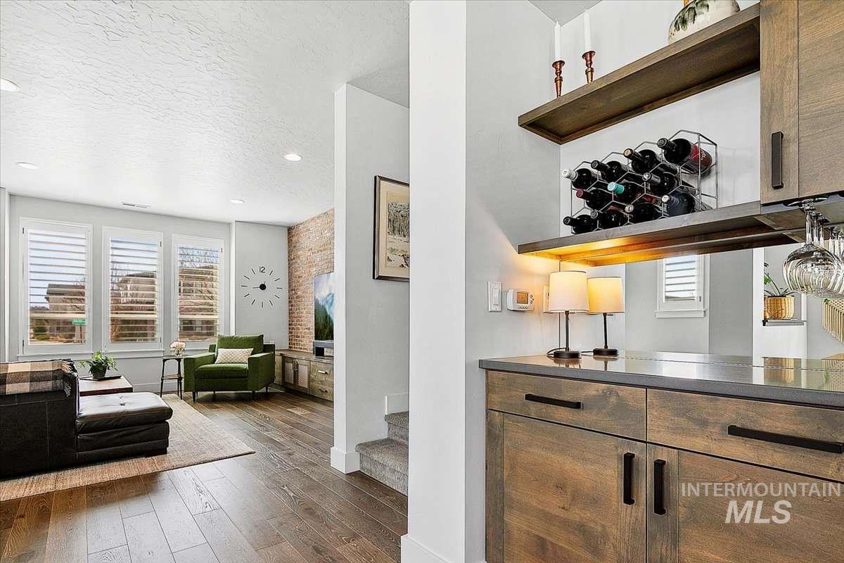 Bar area featuring open shelves, a textured ceiling, healthy amount of natural light, dark wood finished floors, and recessed lighting