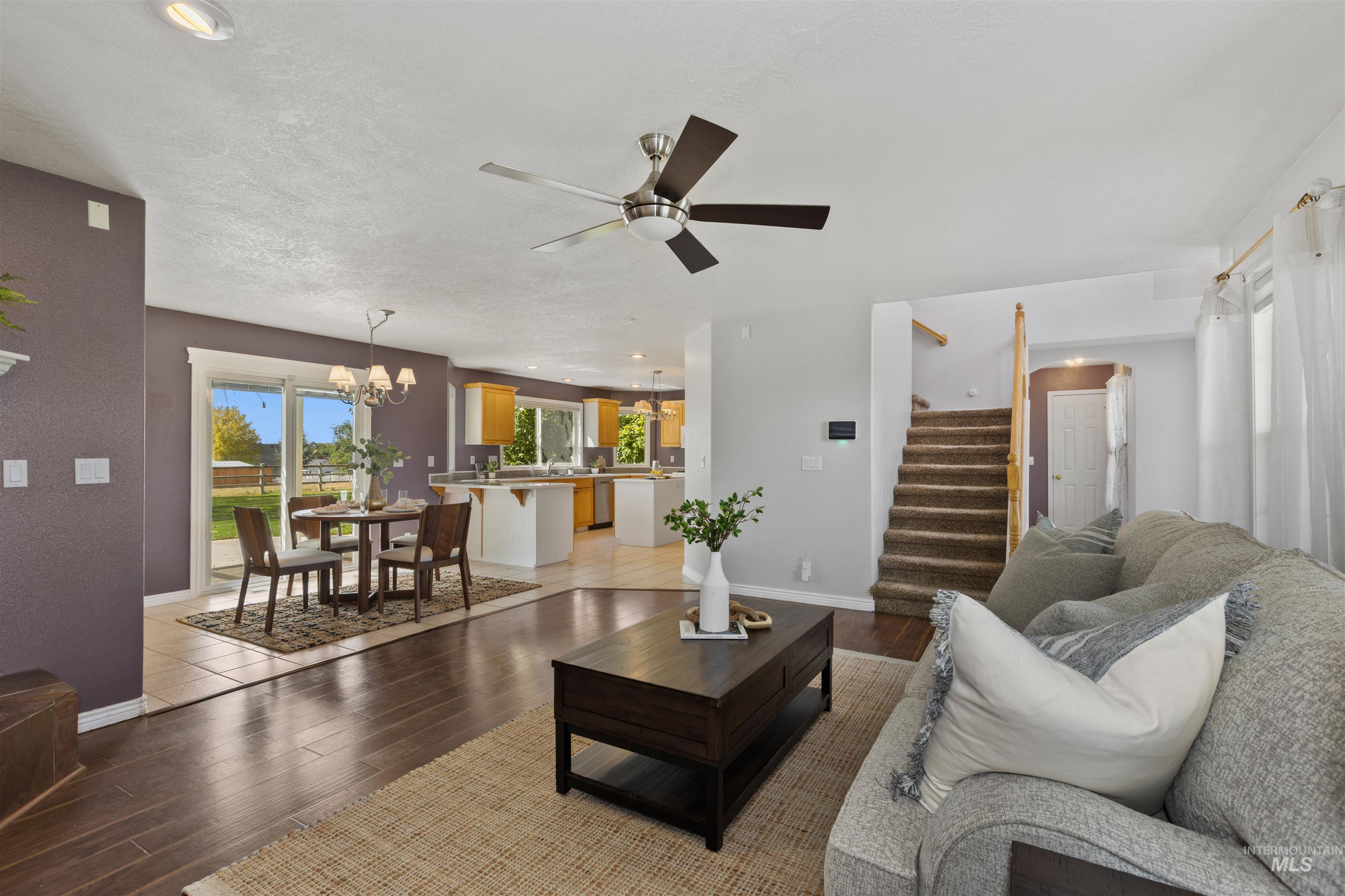 Living area featuring stairway, light wood-type flooring, a chandelier, a ceiling fan, and recessed lighting