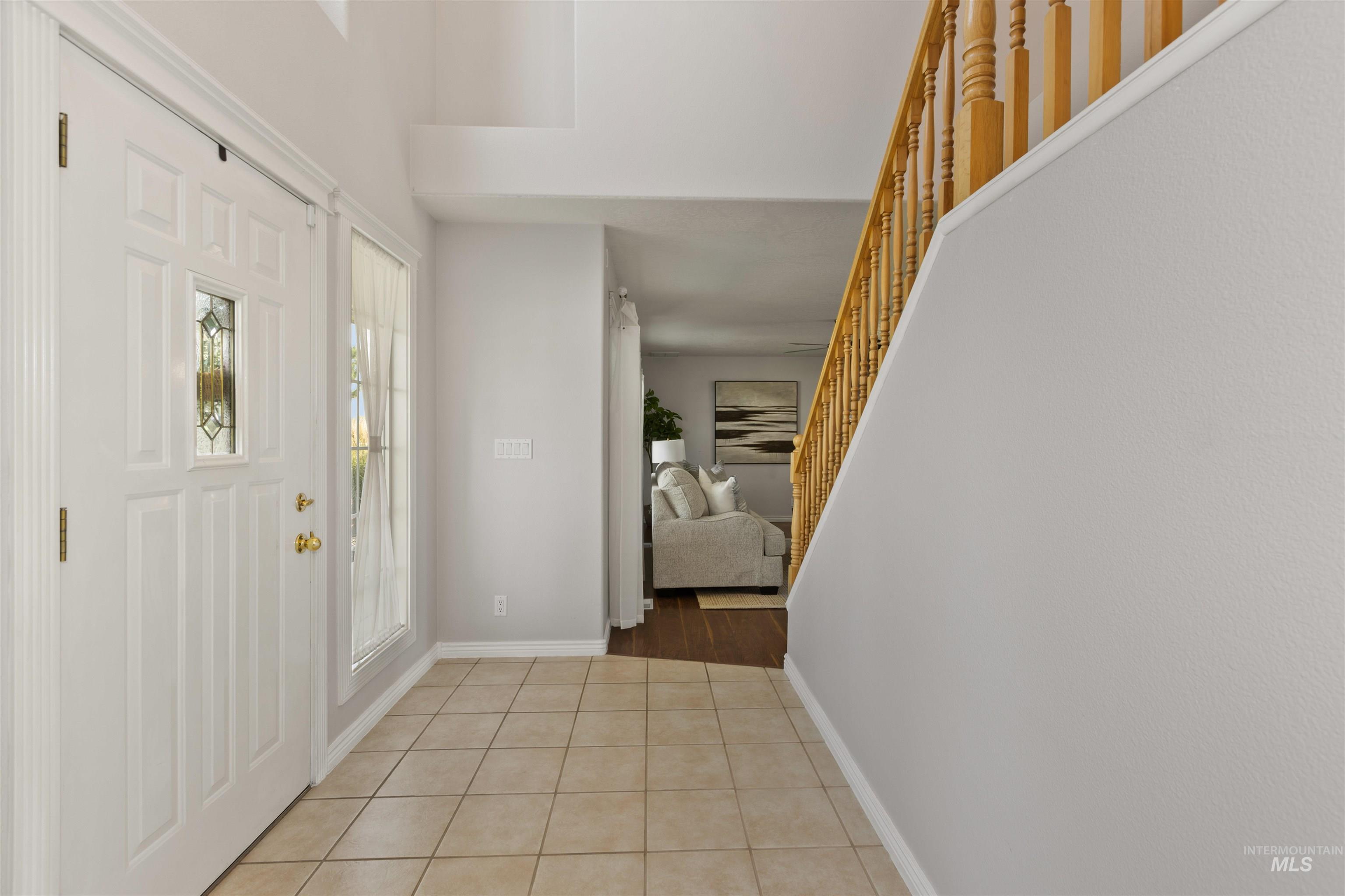 Foyer entrance featuring light tile patterned flooring and stairs