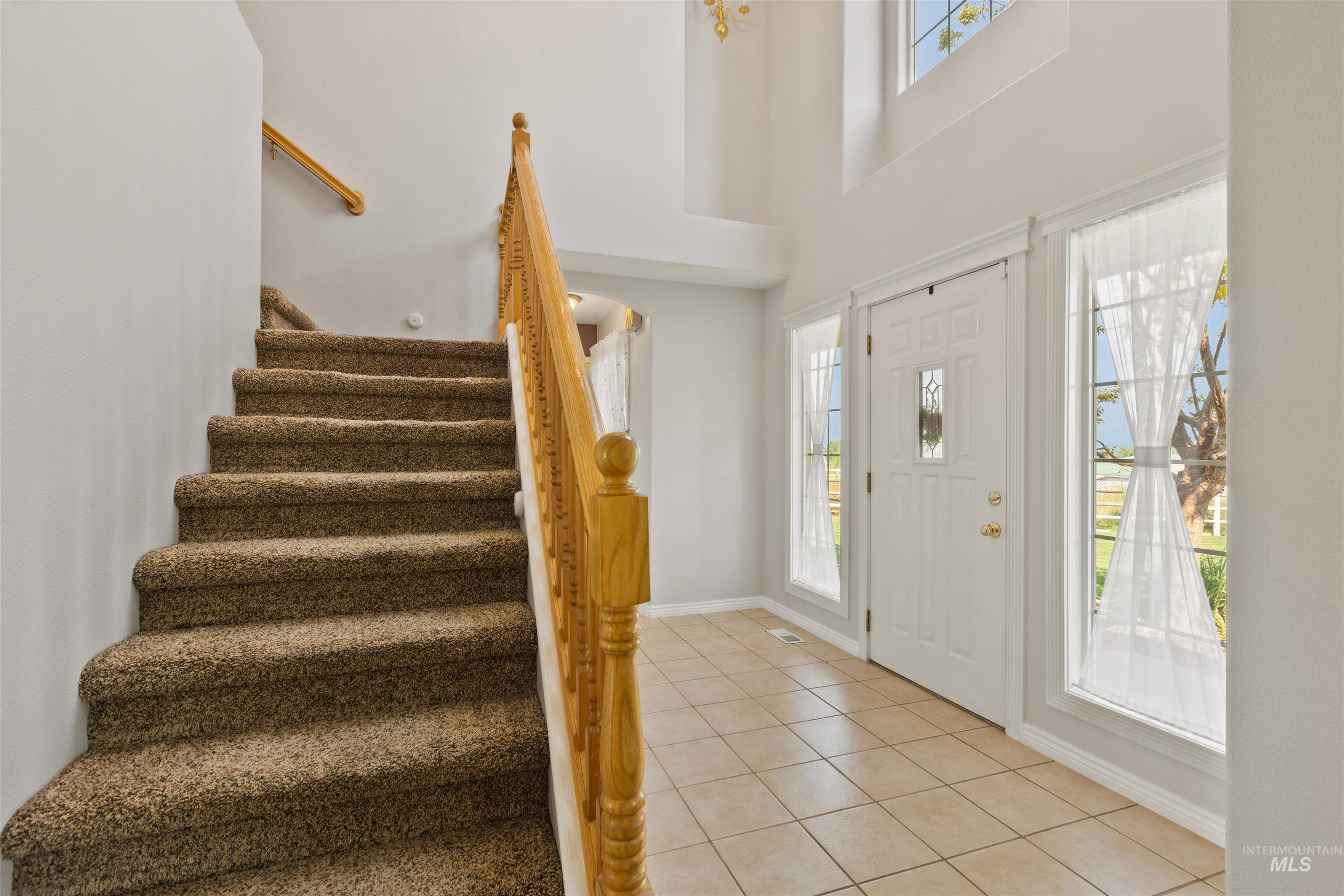 Foyer with light tile patterned floors, stairs, and a towering ceiling