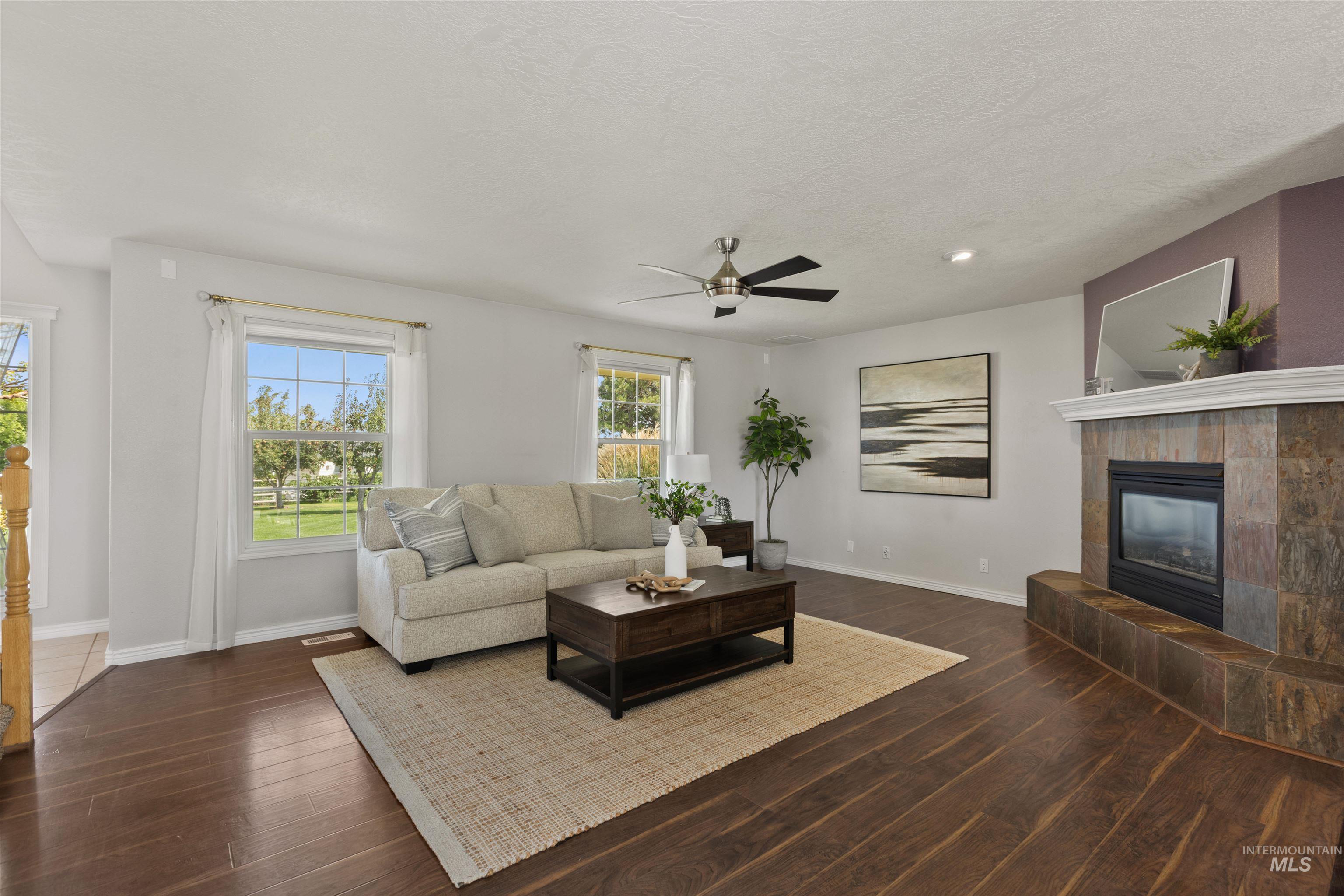 Living room with a fireplace, a ceiling fan, dark wood finished floors, a textured ceiling, and recessed lighting