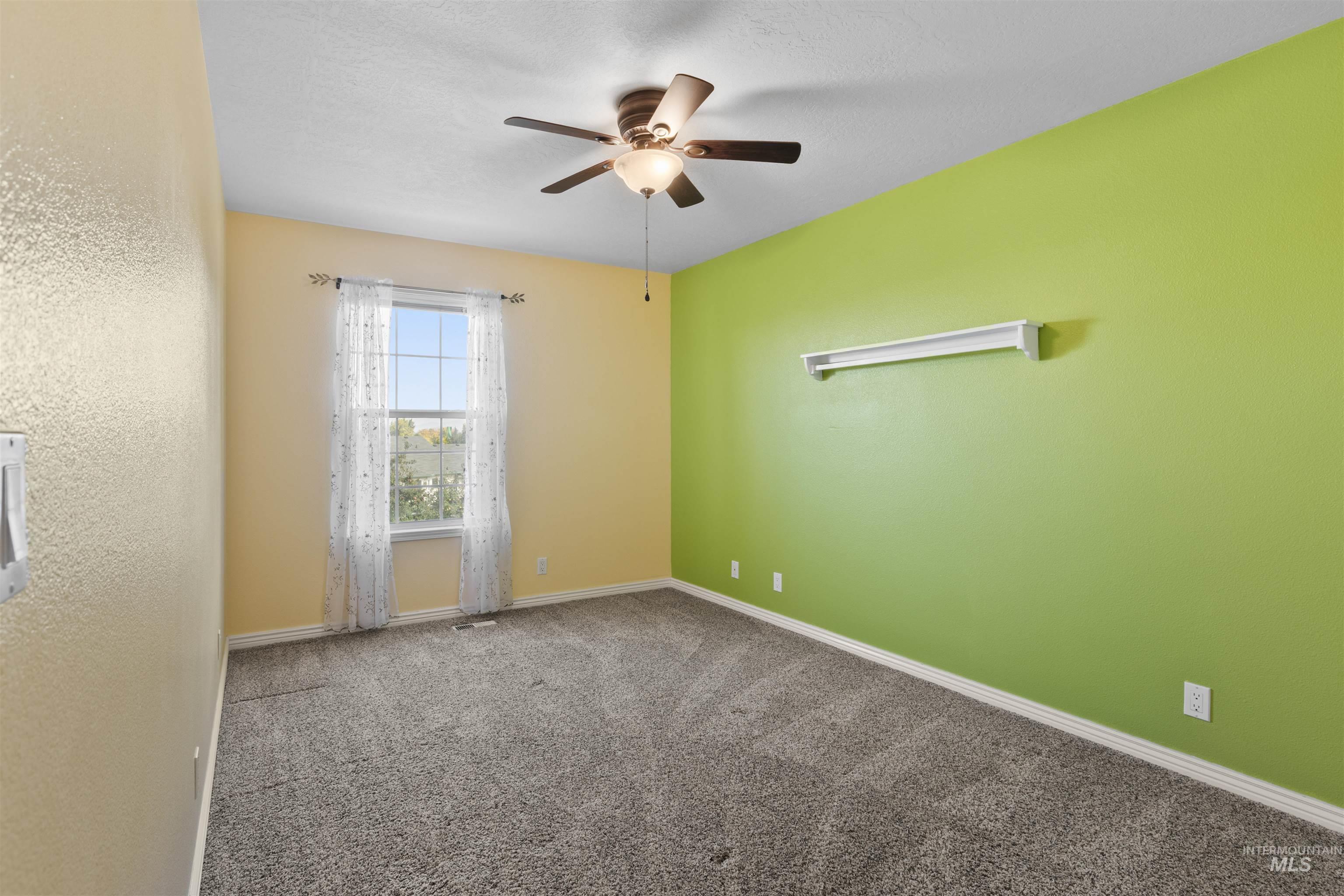 Carpeted empty room with baseboards and a ceiling fan