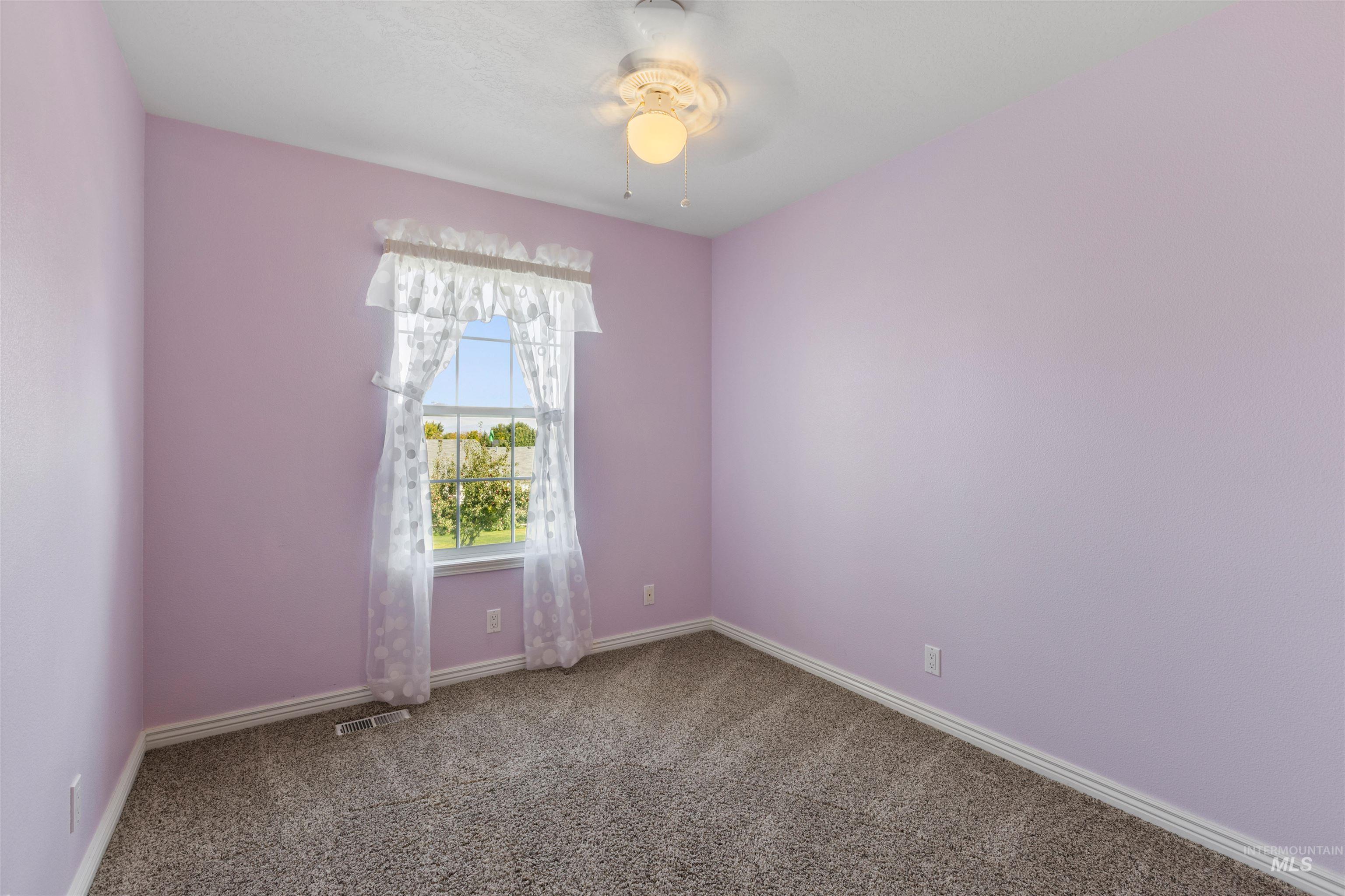 Carpeted empty room with baseboards and ceiling fan